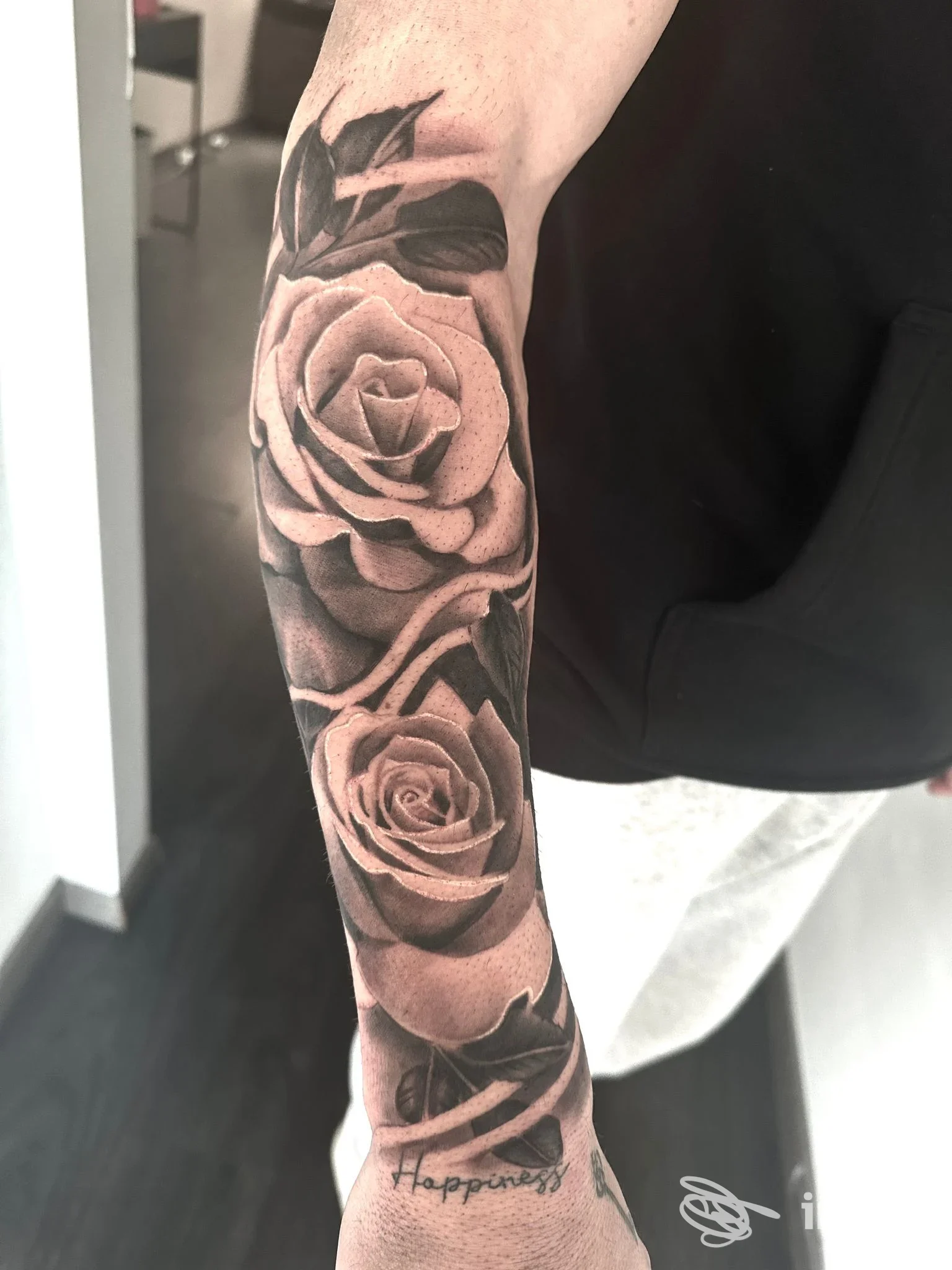 Dettaglio su avambraccio tatuato con due rose realistiche in bianco e nero. The Rose Tattoo studio, Livorno.