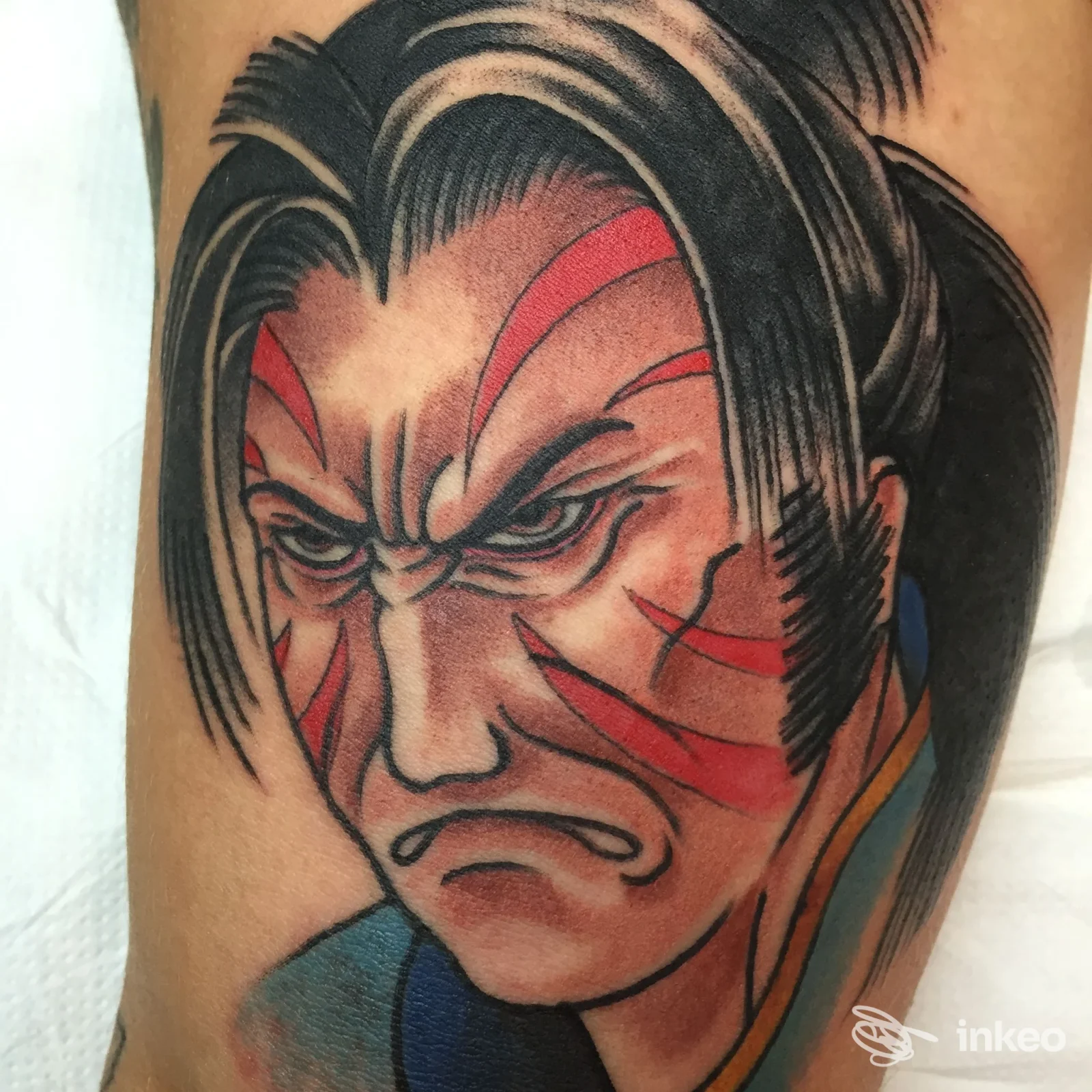 Tatuaggio a colori di un volto stilizzato su avambraccio, Ink Street Tattoo - Glauco Martellini, Orbetello.