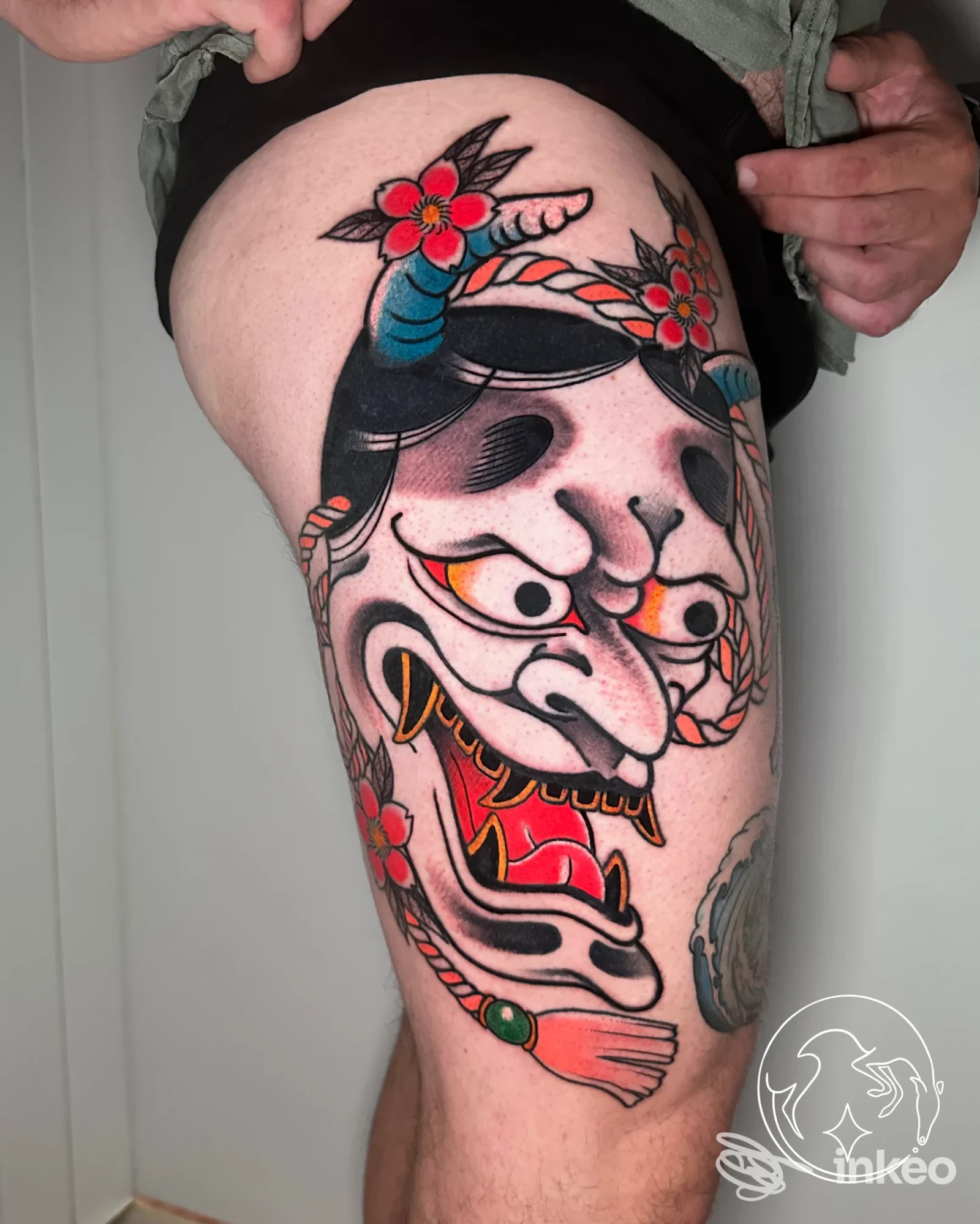 Tatuaggio colorato a tema maschera sulla coscia fotografato in primo piano — ANTEIKU tattoo studio, Piazzola sul Brenta.
