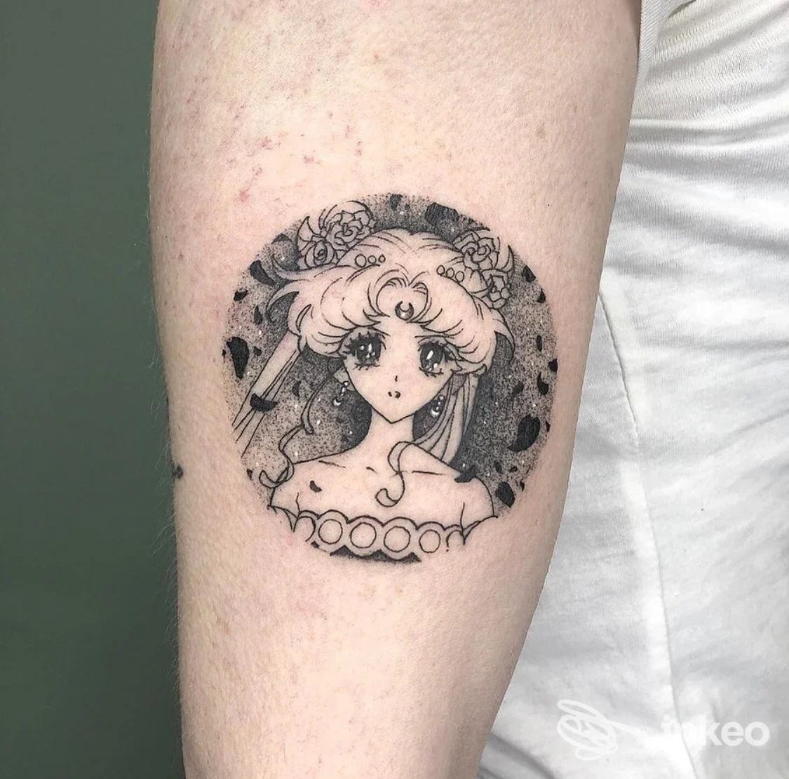 Tattoo su avambraccio raffigurante una giovane ragazza in stile anime, circondata da un cerchio decorativo di fiori, eseguito direttamente sulla pelle.