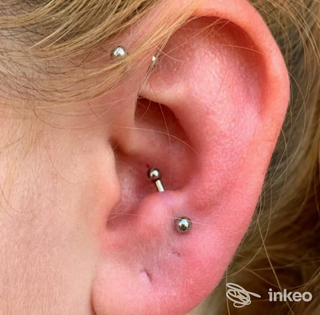 Primo piano di orecchio con tre piercing in metallo, THE KING OF PIERCING, Pinerolo.