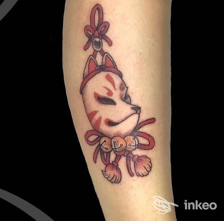 Tatuaggio su avambraccio raffigurante una maschera di volpe stilizzata con fiocchi e nappine, foto fornita da In My Skin TATTOO, Rovigo.