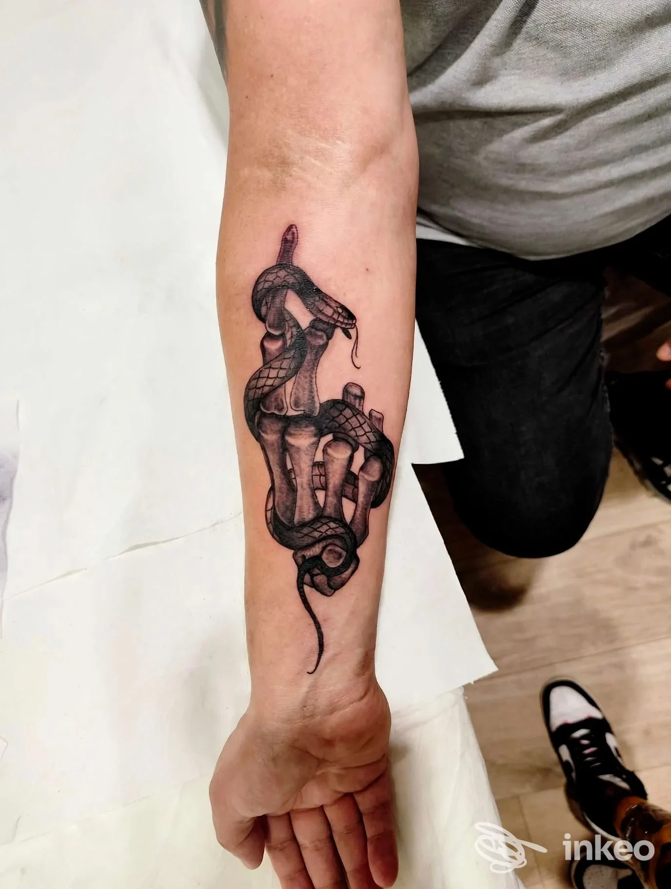 Tatuaggio black/grey di serpente avvolto intorno a una mano scheletrica sull'avambraccio, Marica Emme Tattoo, Matelica.