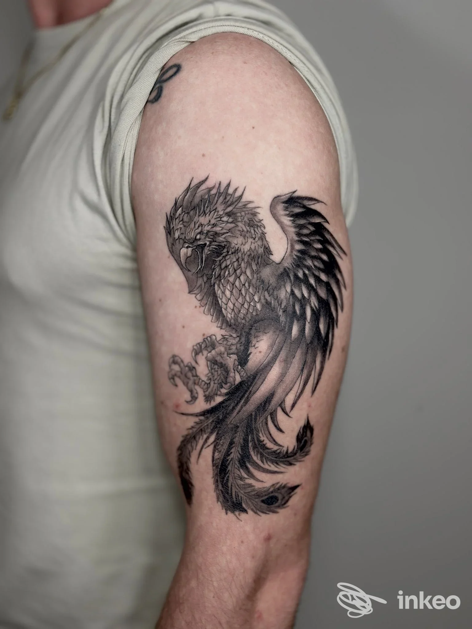 Tatuaggio in bianco e nero a forma di uccello mitologico sul braccio superiore, foto fornita da The Elden Ink Tattoo, Cavallino-Treporti.