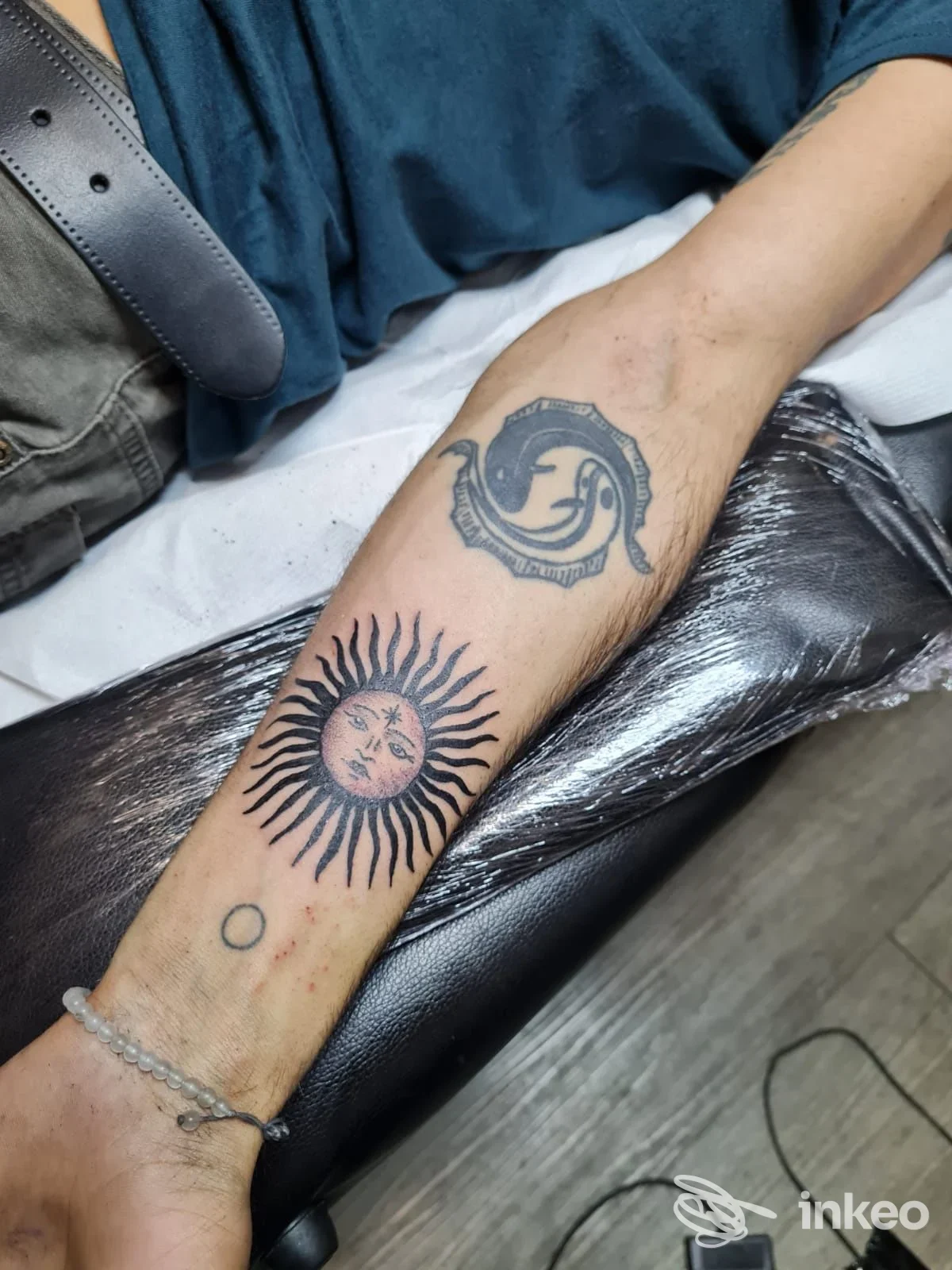 Avambraccio con due tatuaggi (sole stilizzato e motivo circolare) fotografato nello studio Florence Tattoo Studio, Firenze.