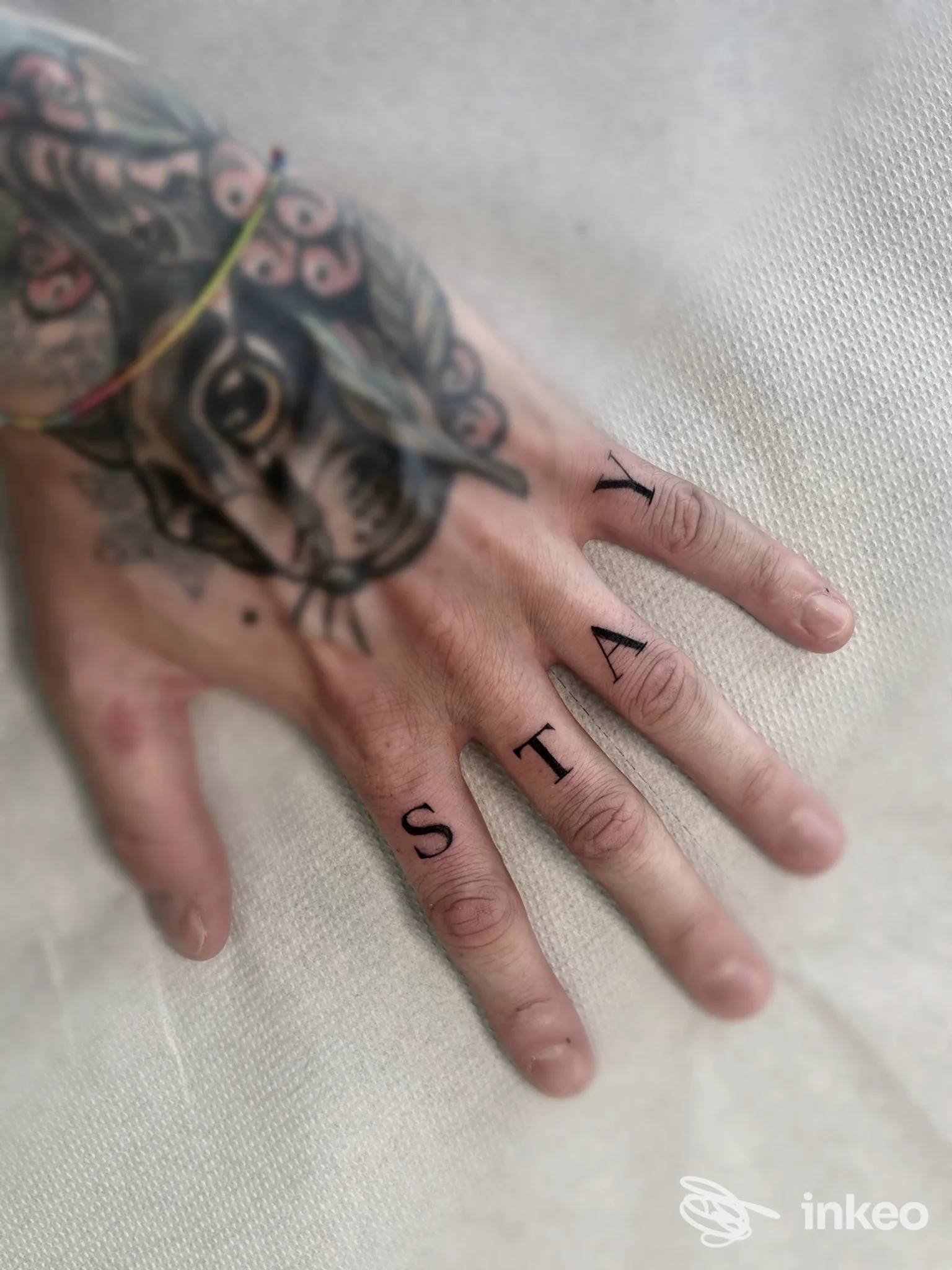Primo piano di una mano tatuata con lettere su quattro dita e un motivo sulla mano, Lara Sun Tattoo & Stregaria Piercing, Porto Tolle.