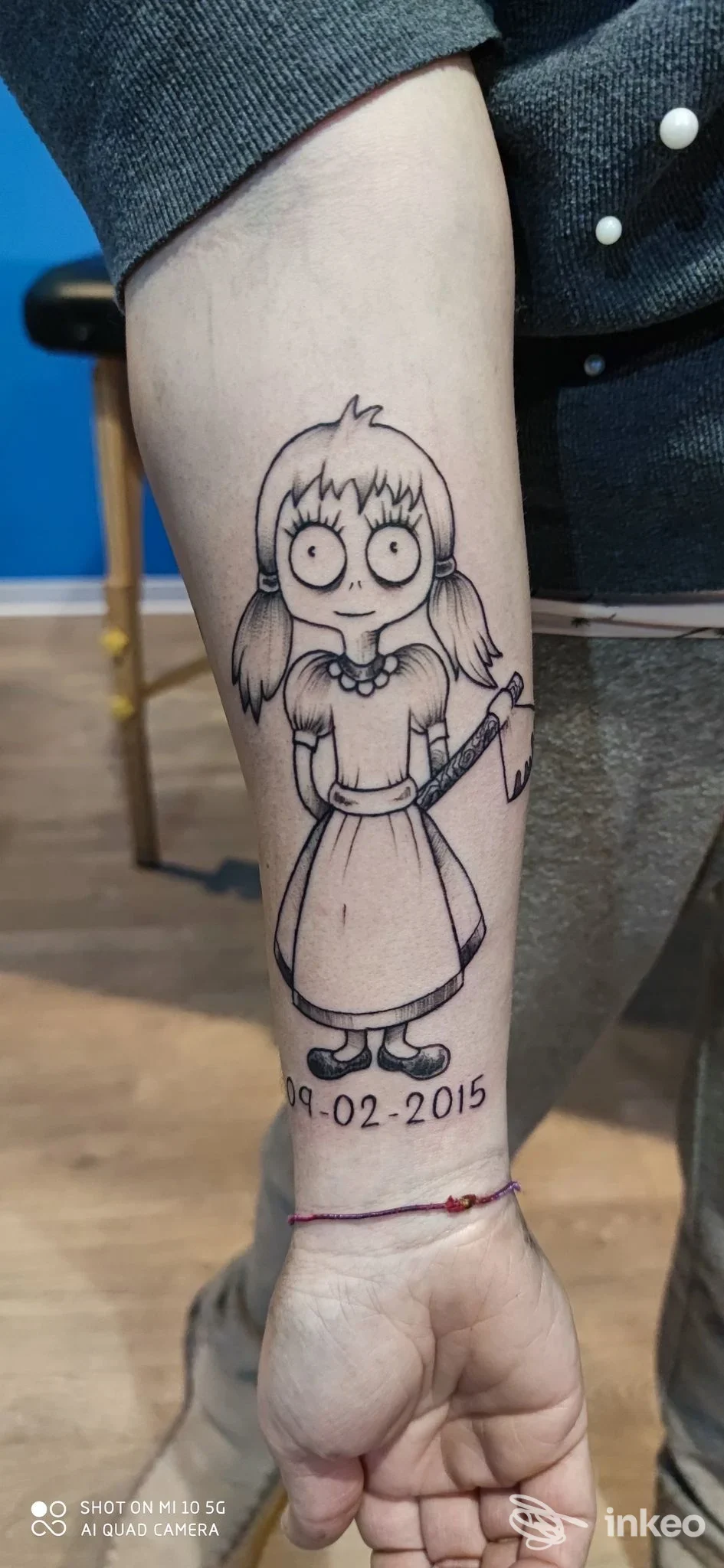 Tatuaggio in bianco e nero di una bambina con ascia sull'avambraccio, Elder Sign Tattoo, Massa Marittima.
