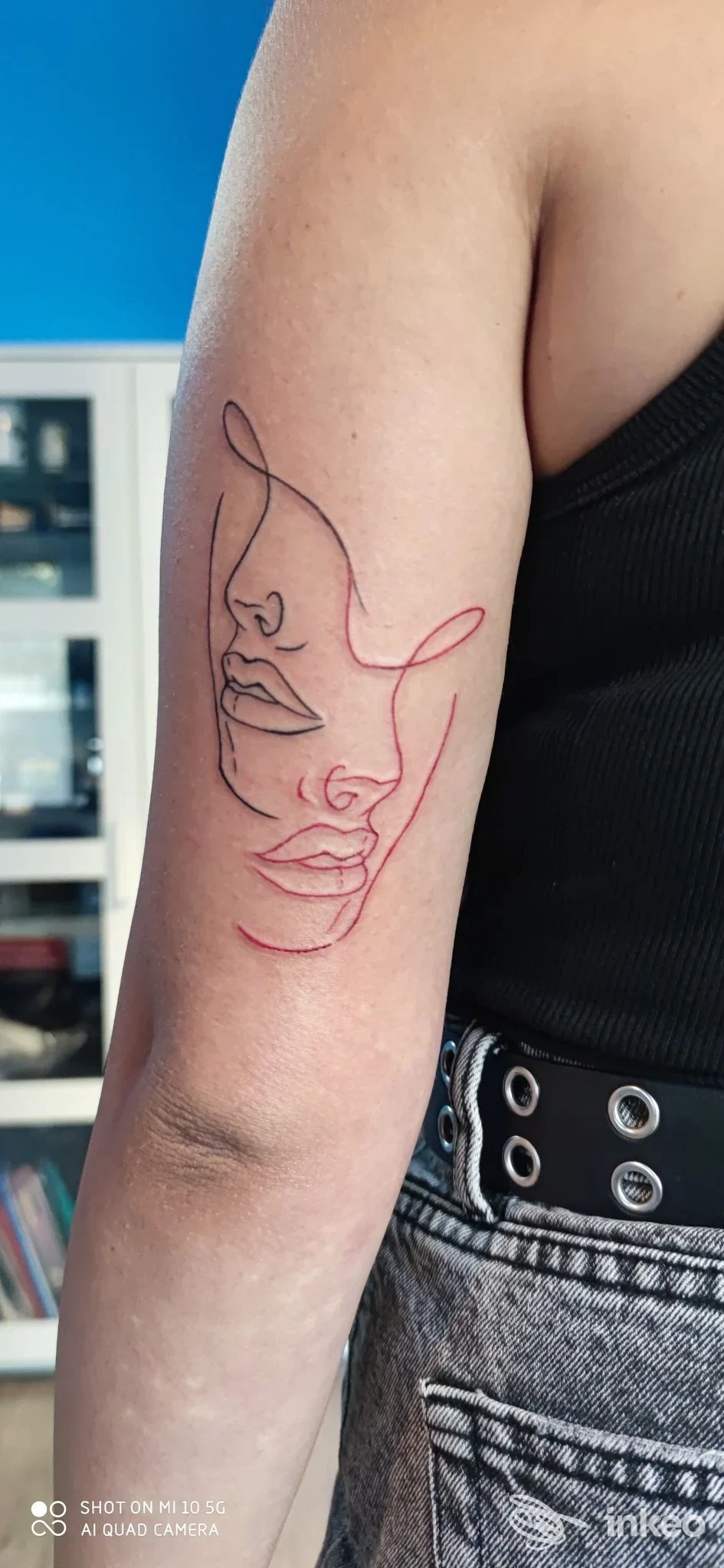 Tatuaggio linee doppie nere e rosse sul braccio superiore, stile line art; foto per Elder Sign Tattoo, Massa Marittima.