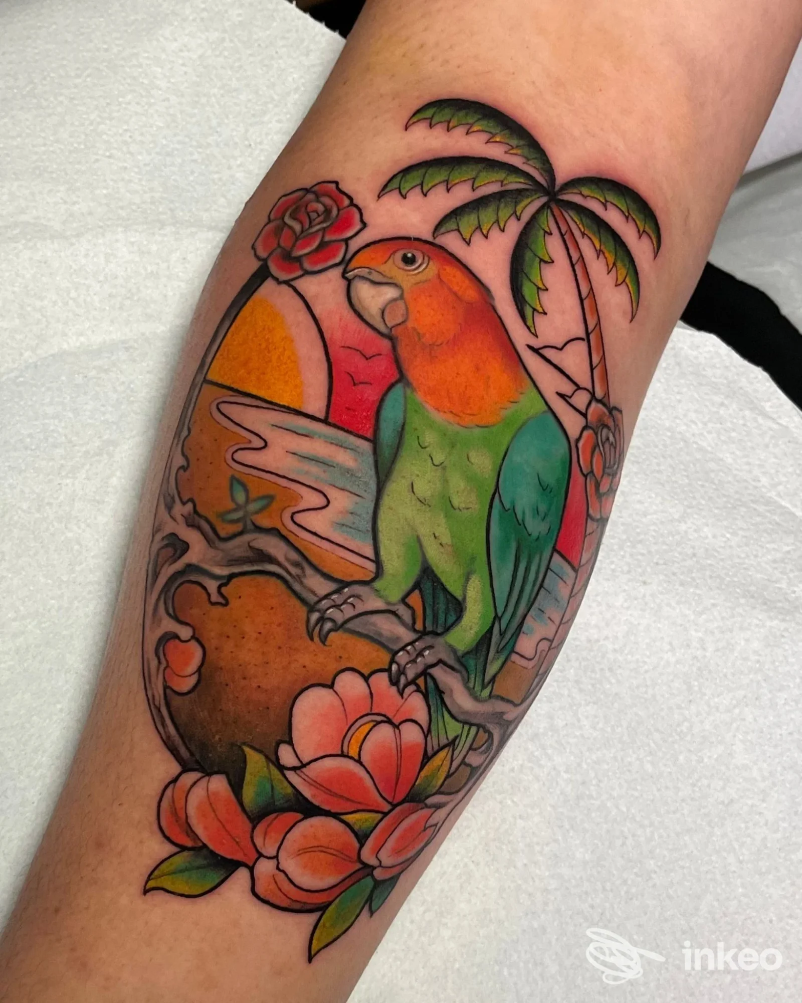 Tatuaggio su avambraccio con pappagallo colorato, fiori e palma — Tuscan Tattoo Studio & Calligraphy Atelier, Prato.