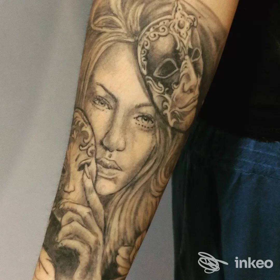 Tatuaggio in bianco e nero su avambraccio con volto femminile e maschere, pubblicato da Frank Tattoo Studio a Sassuolo.