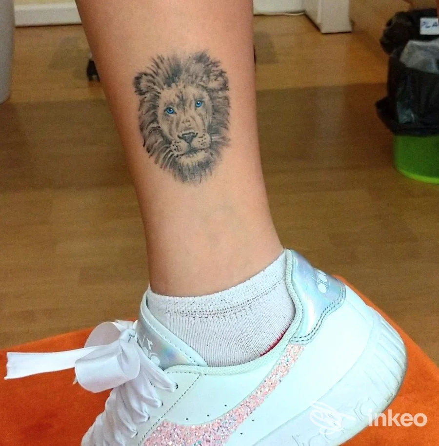 Primo piano di tatuaggio a forma di testa di leone sul polpaccio, fotografato per Frank Tattoo Studio a Sassuolo.