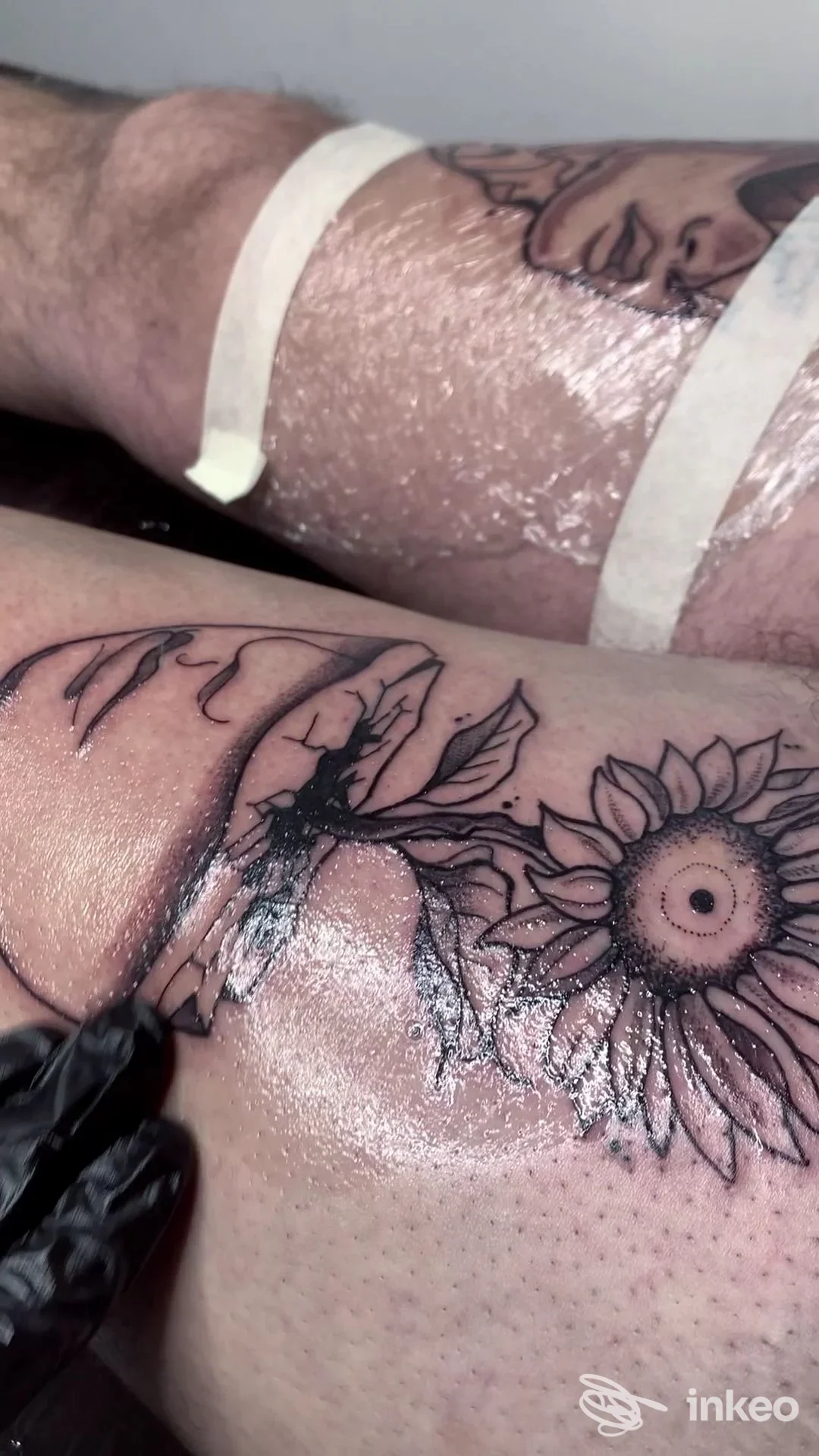 Tatuaggio in corso con girasole su pelle, operatore con guanto nero. The Goldfish Tattoo Studio, Firenze.