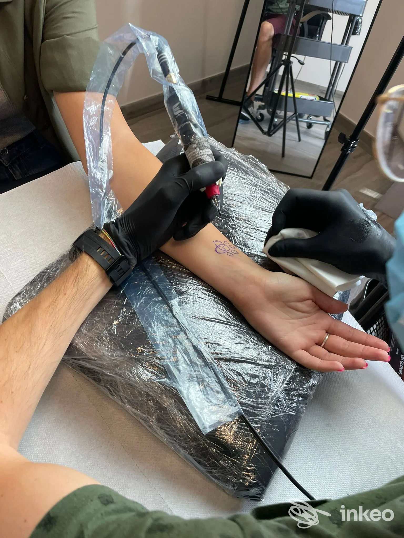 Tatuaggio in corso sul polso in studio Samba Tattoo a Prato, operatore con guanti neri e macchinetta al lavoro.
