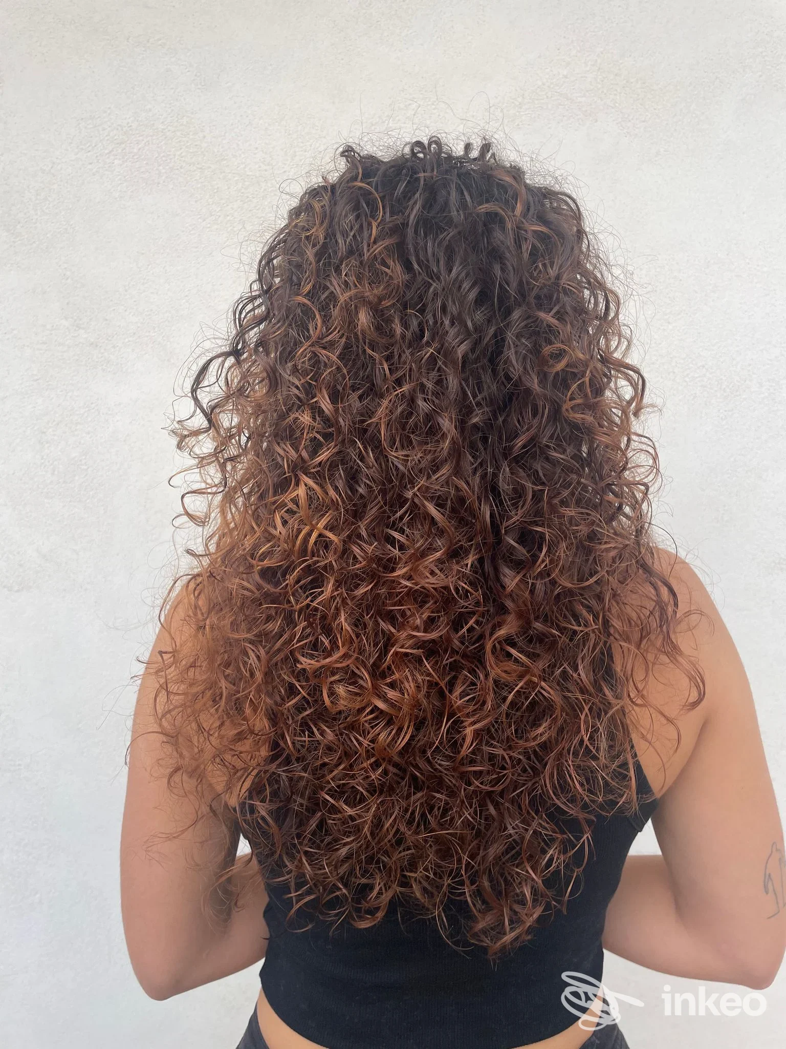 Capelli ricci visti di schiena con piccolo tatuaggio sulla parte superiore esterna del braccio - Medusa Hair & Tattoo Studio, Palma di Montechiaro.