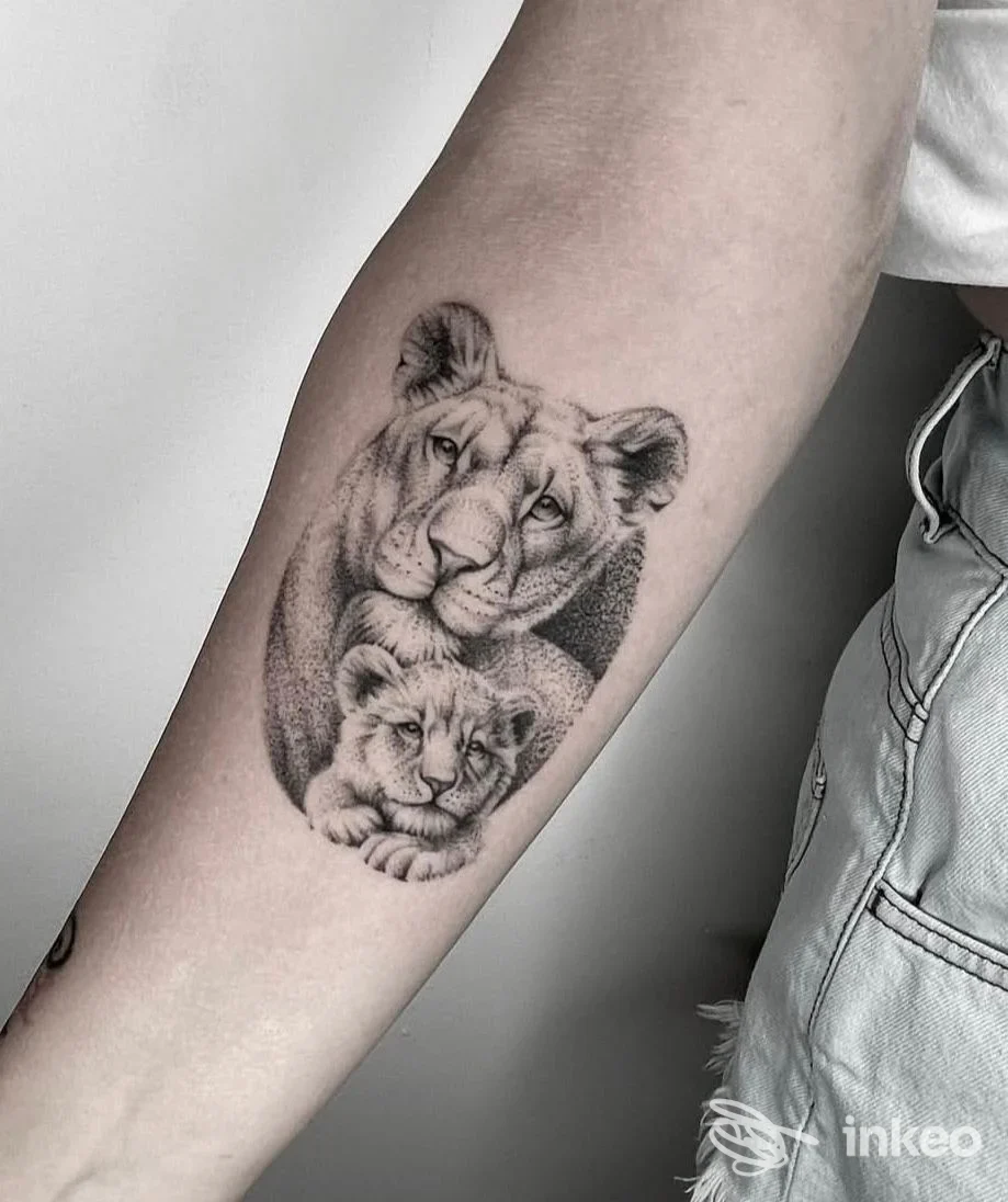 Tatuaggio realistico in bianco e nero di una leonessa con cucciolo sull'avambraccio, foto da Natoora Tattoo Lab a Domodossola.