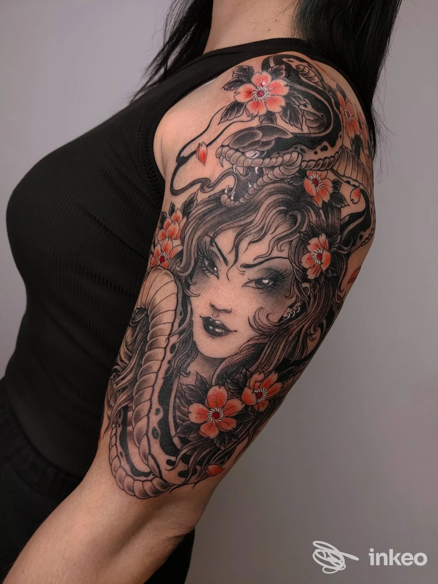 Tatuaggio a mezza manica sul braccio superiore con volto femminile, serpente e fiori arancioni; portfolio, Sakura Tattoo & Piercing Studio, Rovigo.