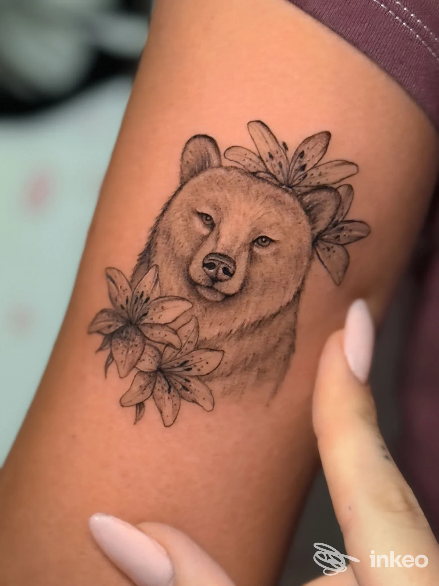 Tattoo raffigurante un cane con fiori sull'avambraccio di una persona; eseguito da The Ink Paradise.