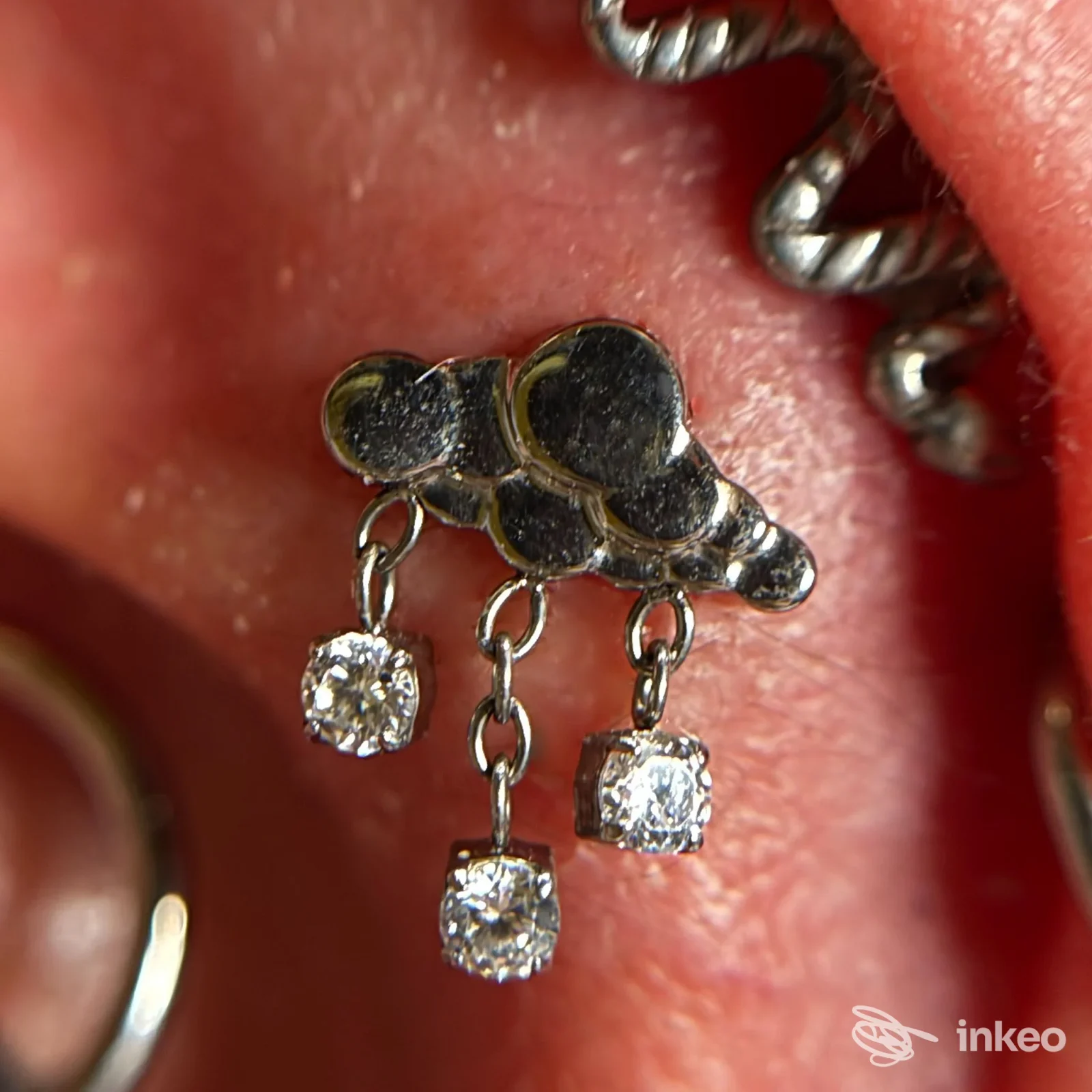 Primo piano su piercing all'orecchio con tre pendenti a catena, foto per Lenya Piercing Studio, Lugo.