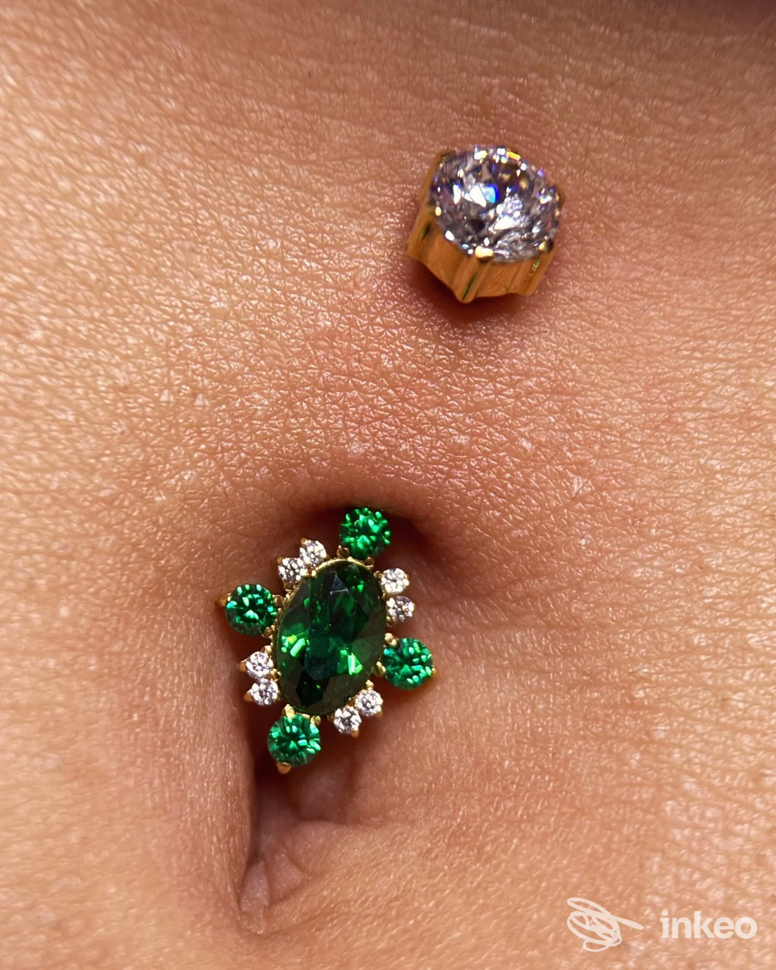 Primo piano di un piercing all'ombelico con gioielli verdi e dorati, Lenya Piercing Studio, Lugo.