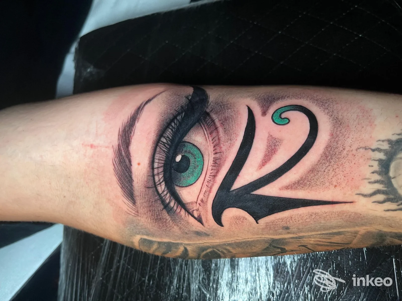 Tatuaggio a Brindisi presso The Family ink: occhio realistico verde con elementi grafici neri sull'avambraccio.