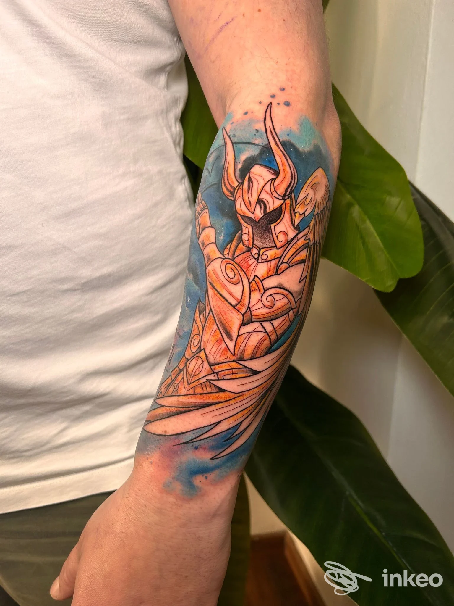 Tatuaggio su avambraccio di figura corazzata con toni blu e arancio, La Bea Tattoo Studio, Cesena.