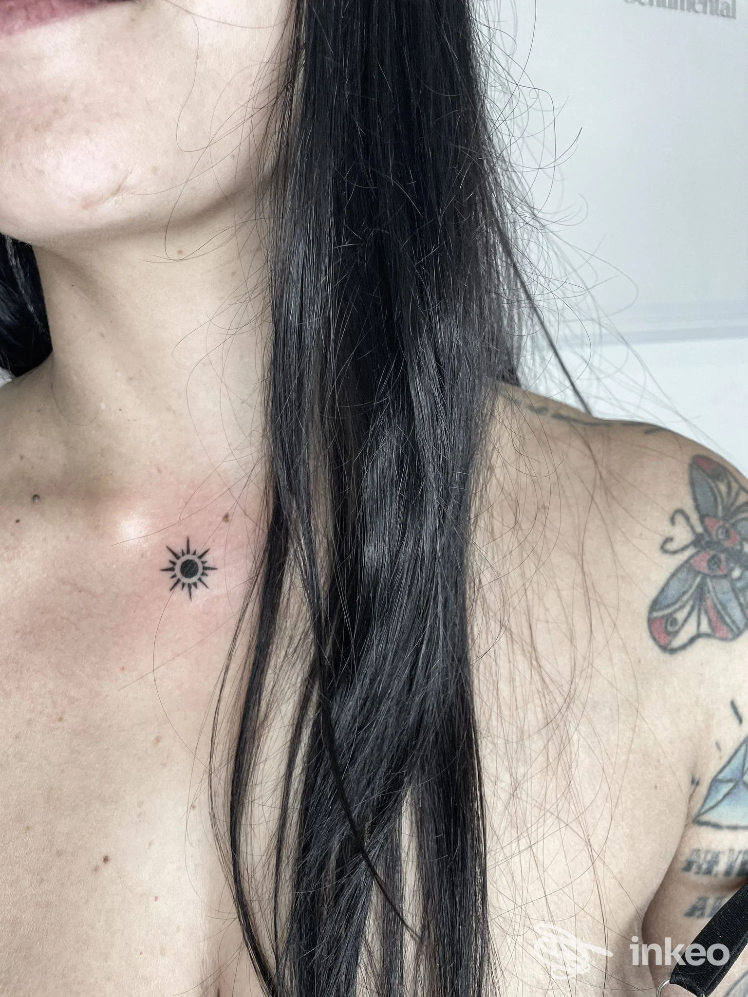 Piccolo tatuaggio a forma di sole sotto la clavicola sinistra e tatuaggio a farfalla sulla spalla, foto da Edera tattoo art, Perugia.
