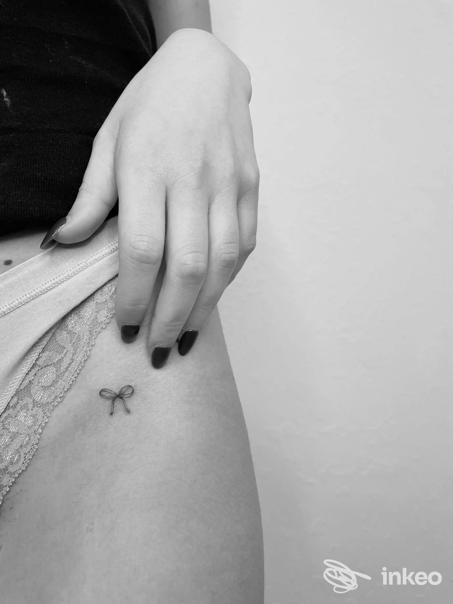 Piccolo tatuaggio a forma di fiocco sulla coscia superiore, fotografia di Edera tattoo art a Perugia, dettaglio in bianco e nero.
