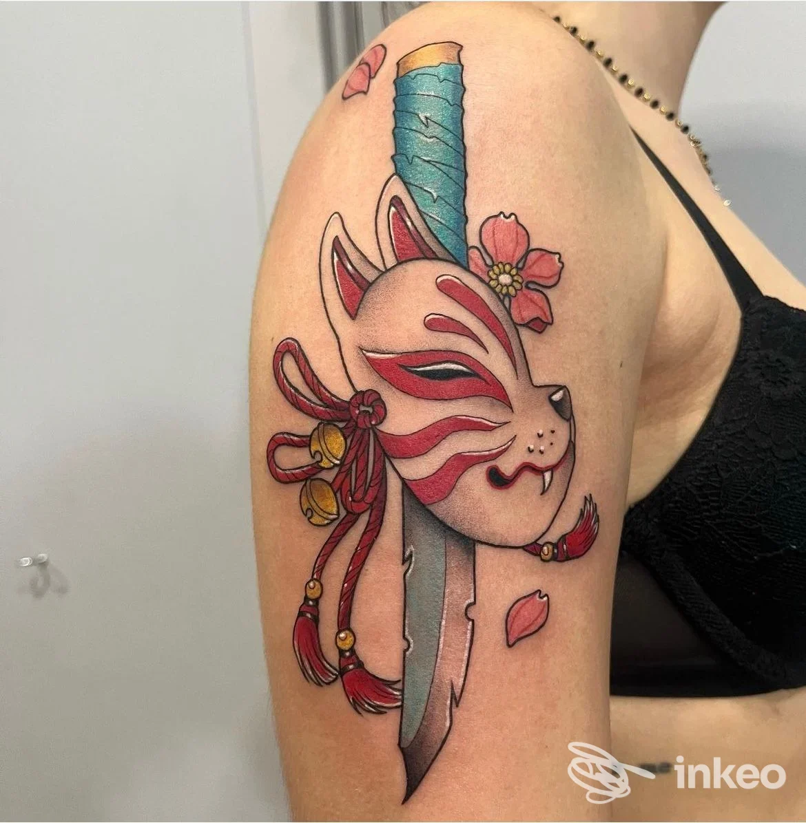 Tatuaggio a colori su braccio superiore: maschera kitsune con pugnale e fiori. Electric Tattoo Studio, Asti.