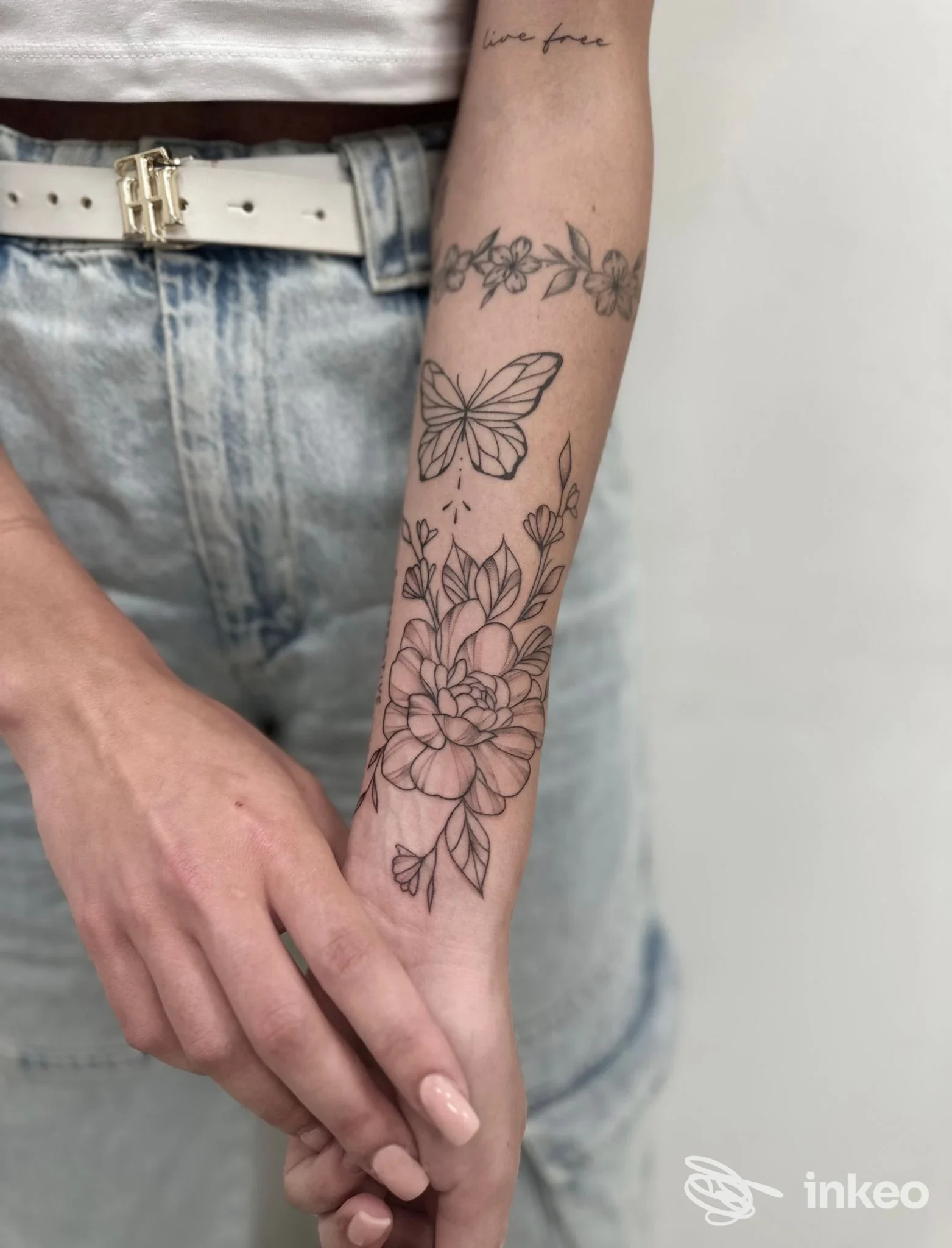 Tatuaggio a linee fini con fiore e farfalla sull'avambraccio, foto fornita da Black Family Ink, Pozzallo.
