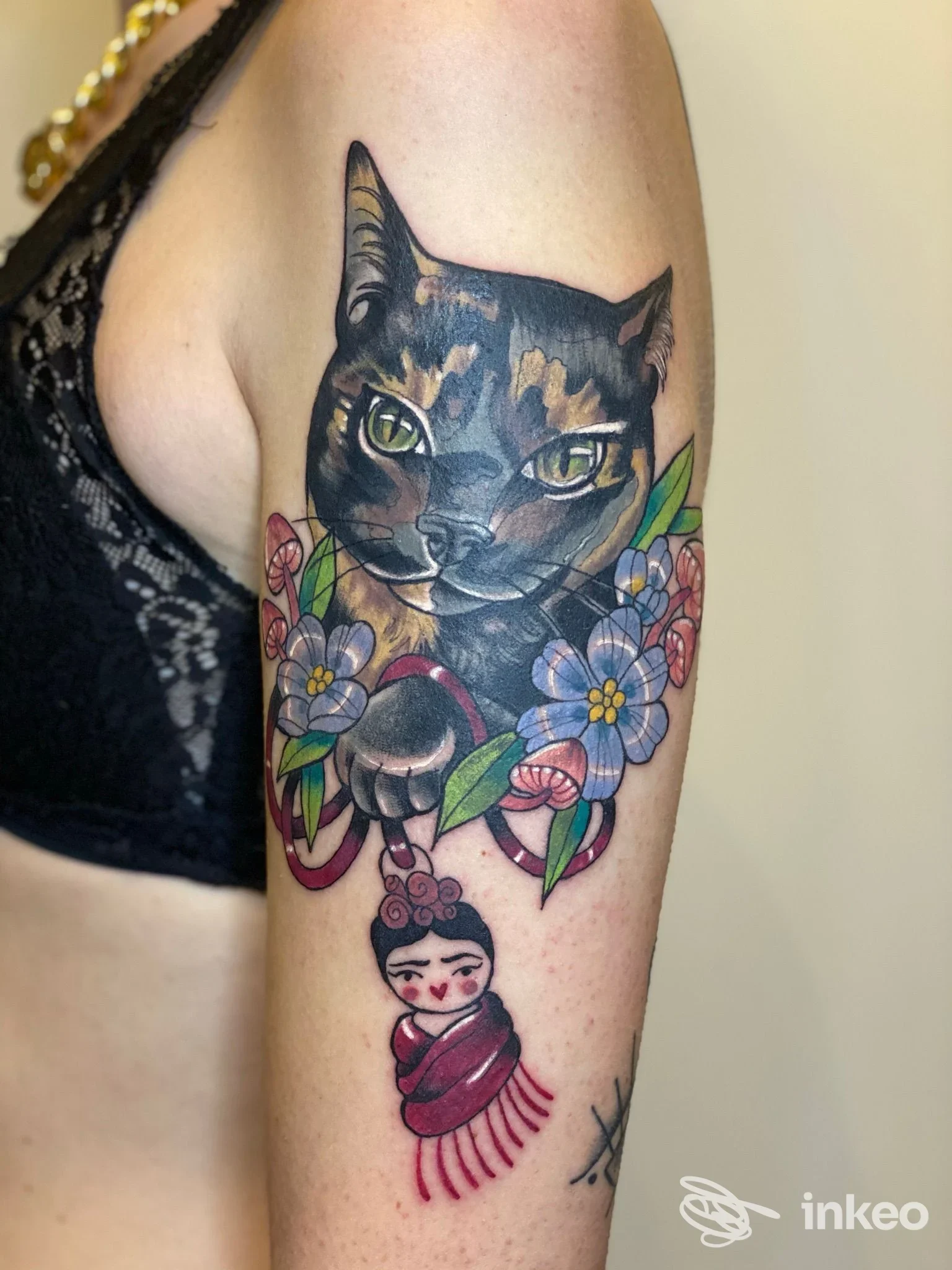 Tatuaggio colorato di testa di gatto con fiori sul braccio superiore, realizzato da Supercalifragil Ink Tattoo Shop a Porto Viro.