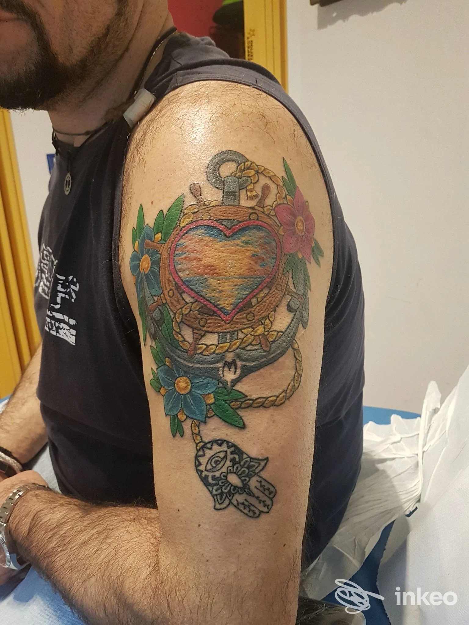Tatuaggio colorato su braccio superiore con cuore, ancore e fiori. Respect Tattoo, Stanghella.
