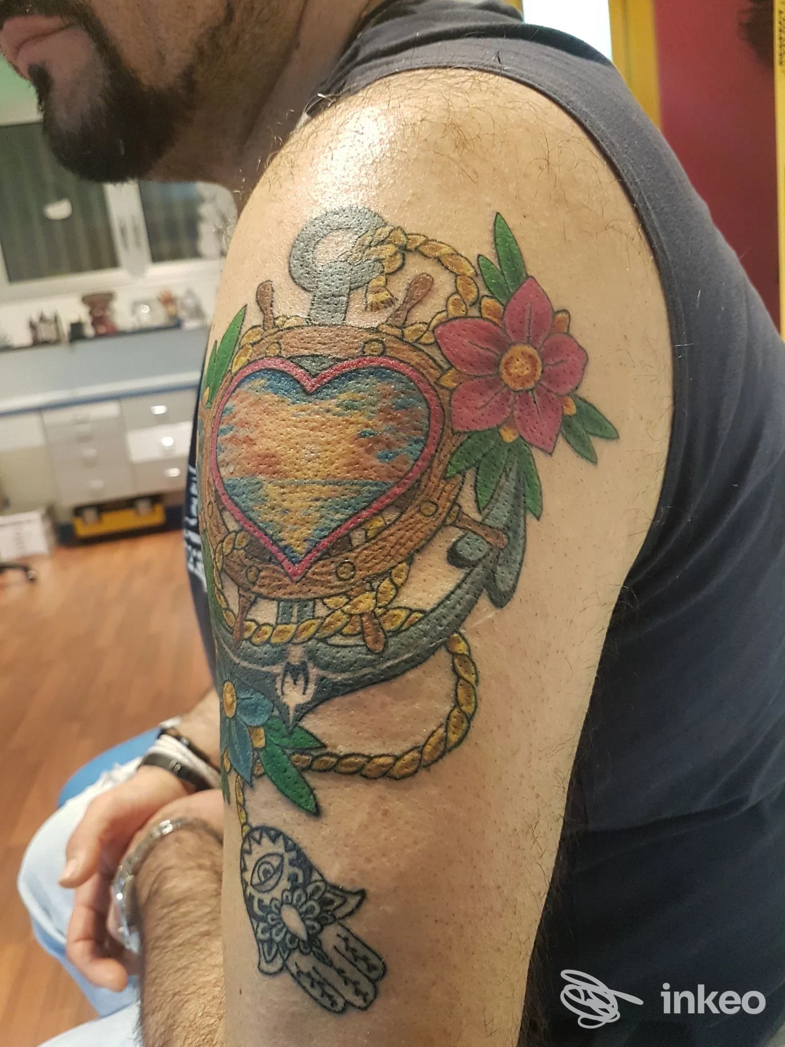 Tatuaggio colorato a cuore con ancora e fiori sullʼavampalla di un uomo, foto fornita da Respect Tattoo, Stanghella.