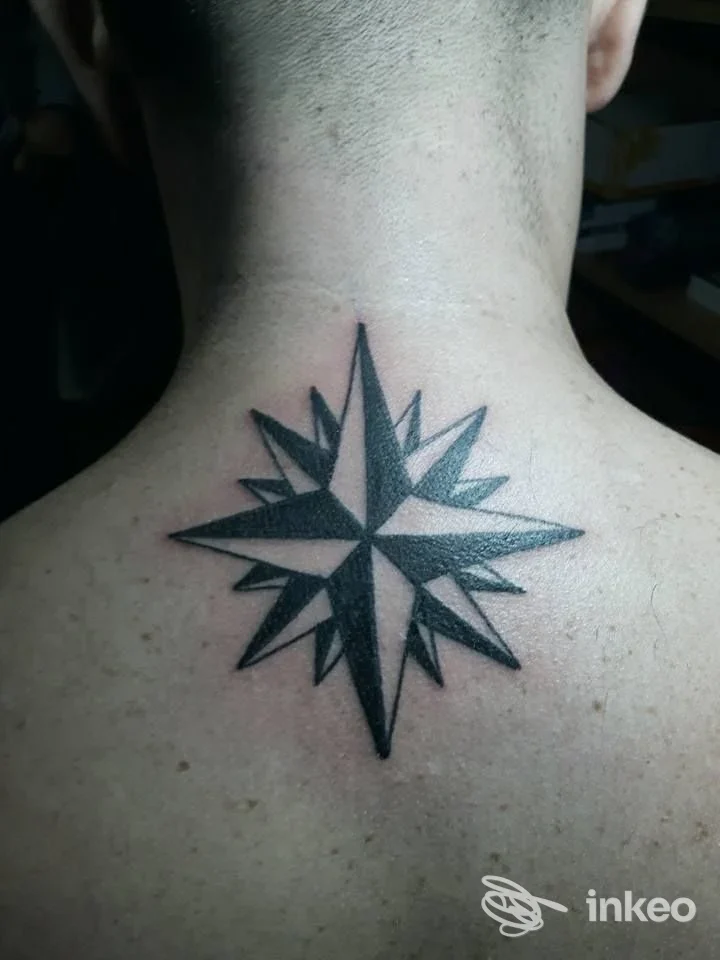 Tatuaggio nero a forma di rosa dei venti sulla nuca, foto fornita da Boaz Tattoo Prato, Prato.