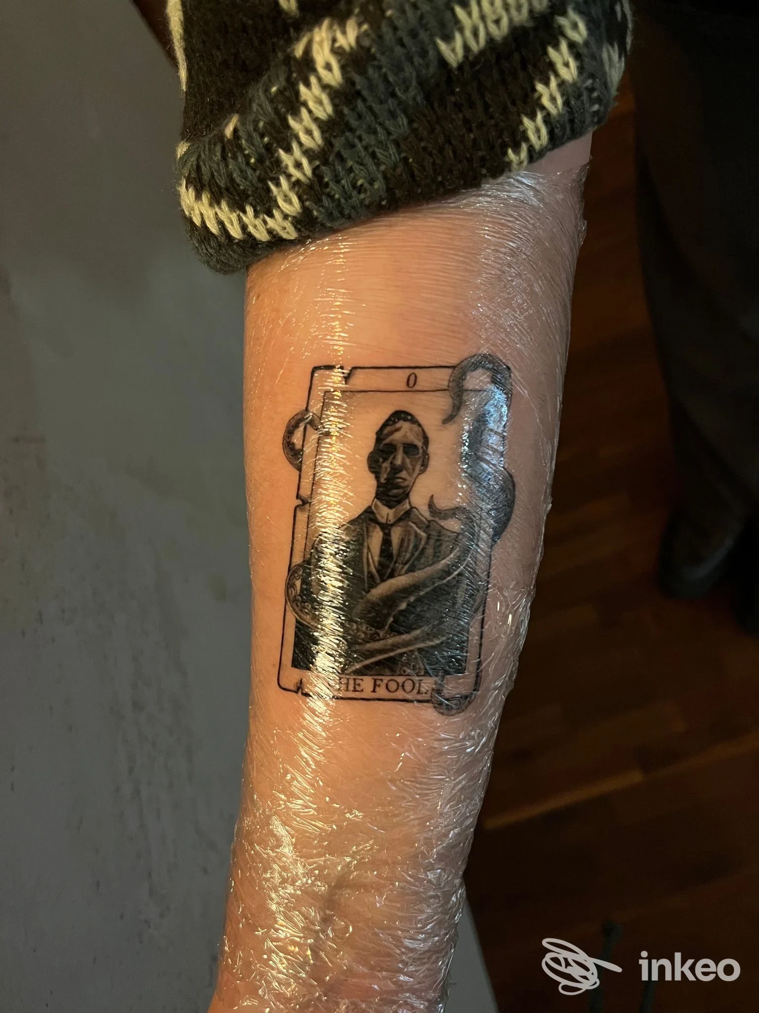 Tatuaggio sull'avambraccio a Ravenna eseguito da Quiete: ritratto in stile carta da gioco avvolto nella pellicola protettiva.