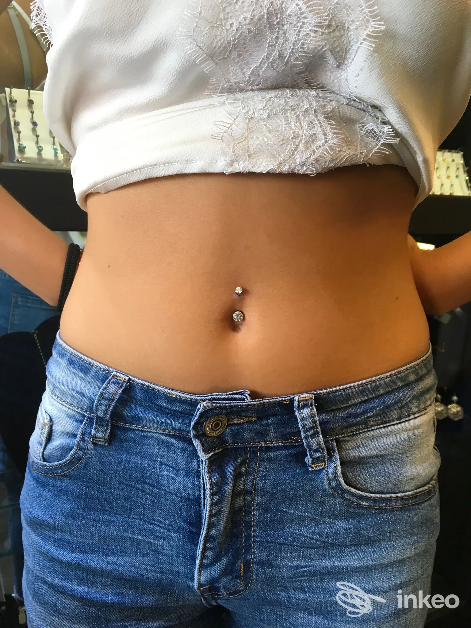 Primo piano di un piercing all'ombelico realizzato da ADRENALINE STUDIO Tattoo & Piercing a Follonica, con top corto e jeans.