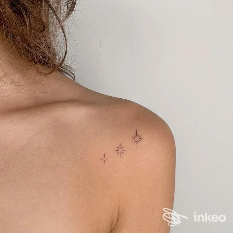 Piccolo tatuaggio a quattro stelle minimal sulla spalla sinistra, foto ravvicinata. Il trucco di Roby, Valenza.