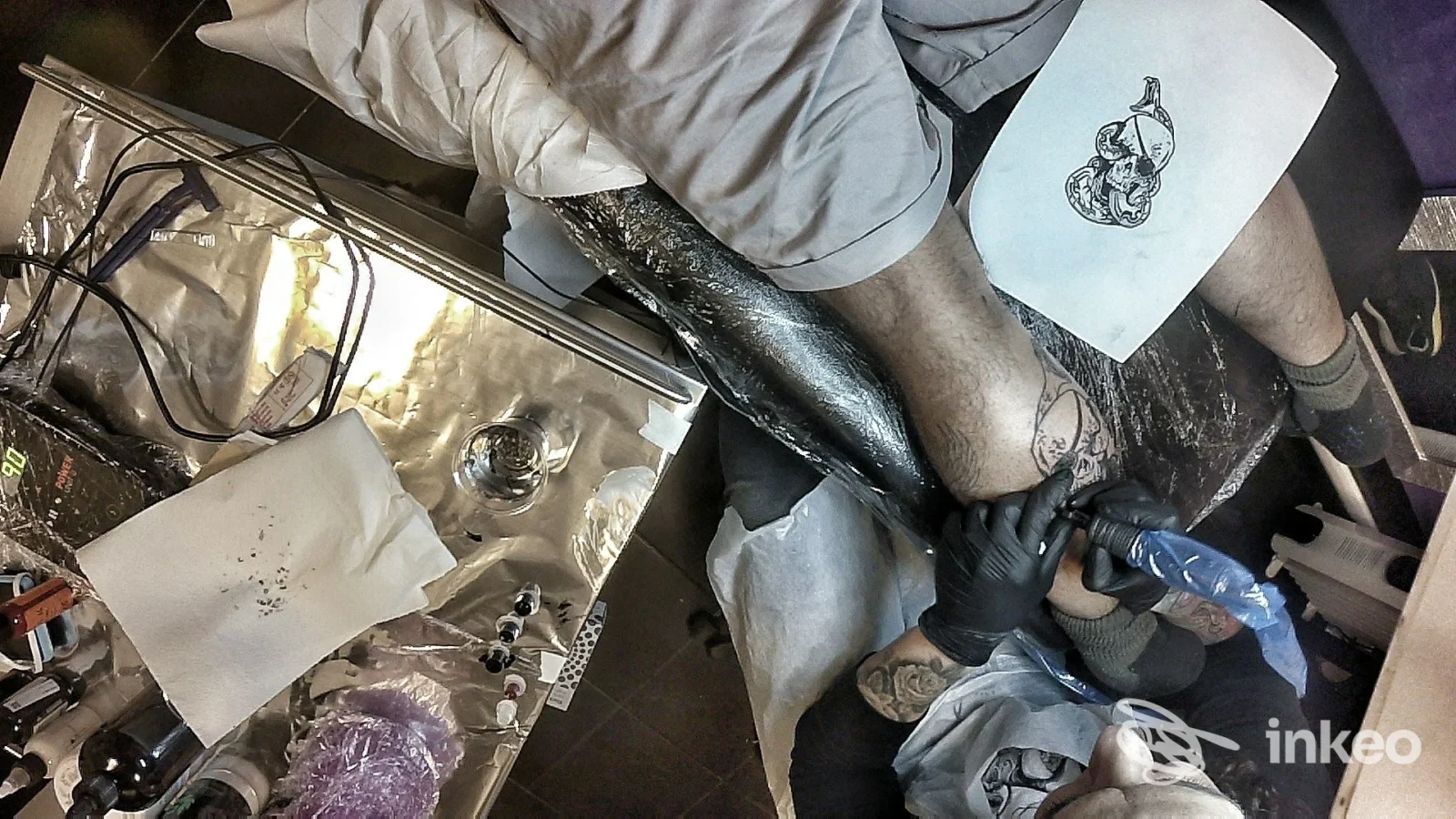 Tatuaggio in corso su una gamba nello studio Il Giglio Nero Tattoo a Campi Bisenzio, operatore al lavoro con guanti neri.