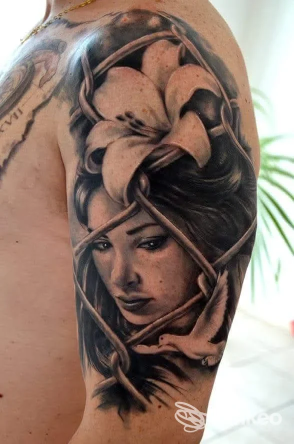 Tatuaggio a mezzo manica sul braccio superiore con ritratto femminile, giglio e fili intrecciati, foto per Bodysigns Tattoos Conversano.