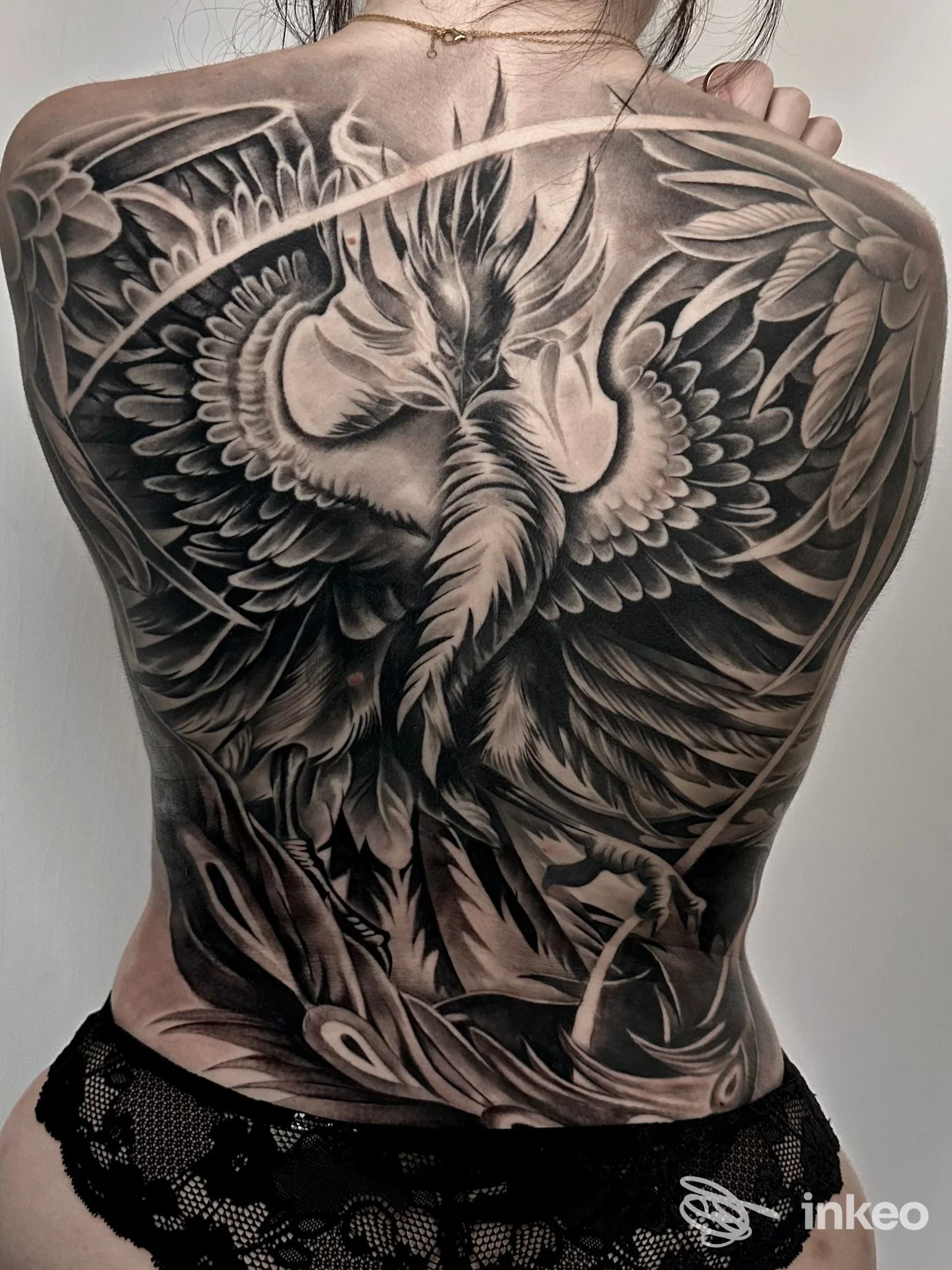 Ampia schiena tatuata con un grande uccello mitologico in bianco e nero, foto fornita da Giuly Tattoo Studio, Biella.