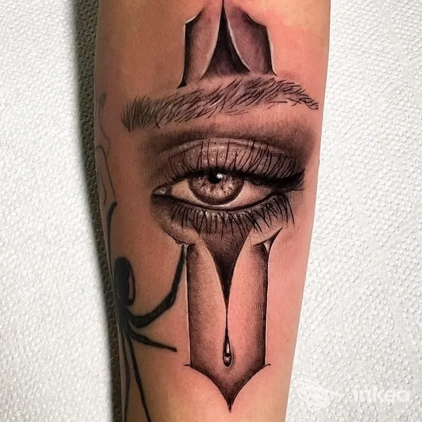 Tattoo realistico sull’avambraccio raffigurante un occhio, con tratti scuri e decorazioni, visibile su pelle reale.
