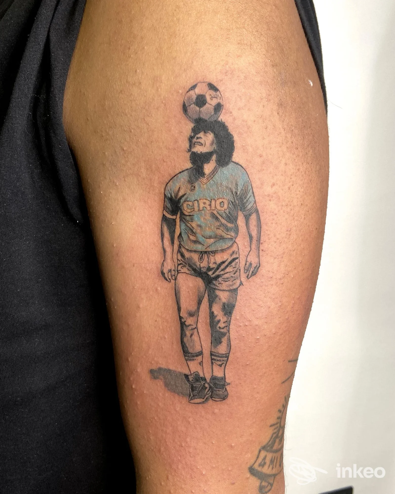 Tatuaggio ritratto realistico di un calciatore con pallone sul capo, eseguito sul braccio superiore. Immagine dal portfolio Santoryu Ink, Rapallo.