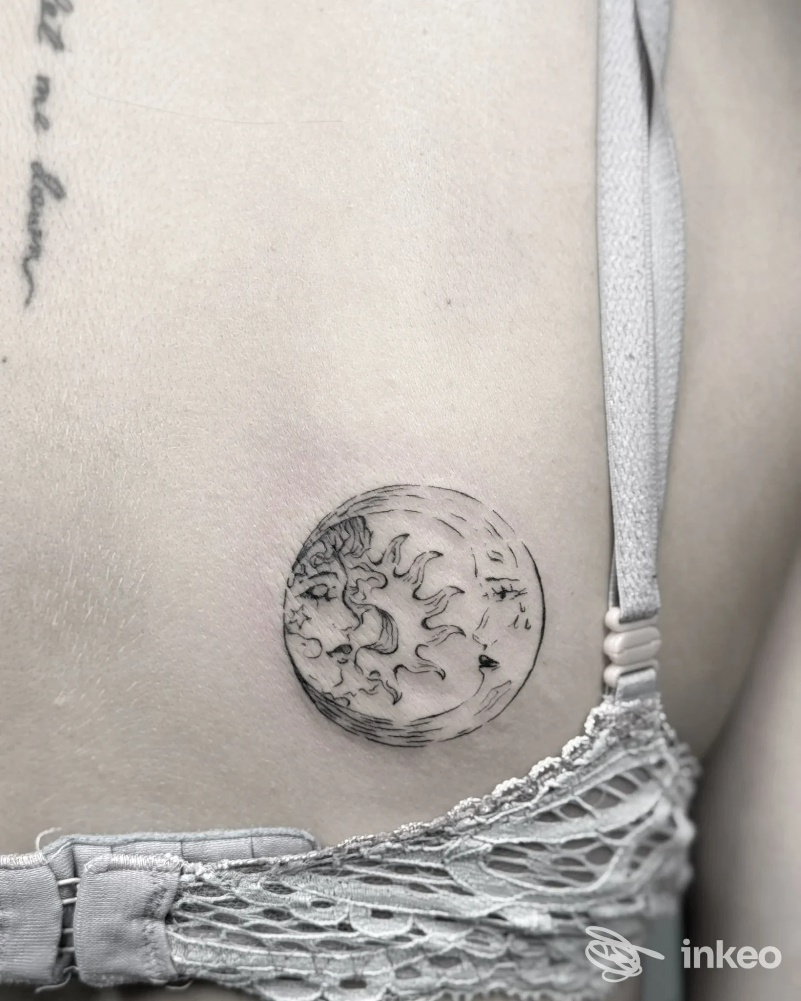 Piccolo tatuaggio circolare in nero con sole e dettagli lunari sul fianco sinistro, lavoro realizzato da Ink Studio Civico 13 by Santa a Santa Margherita Ligure.