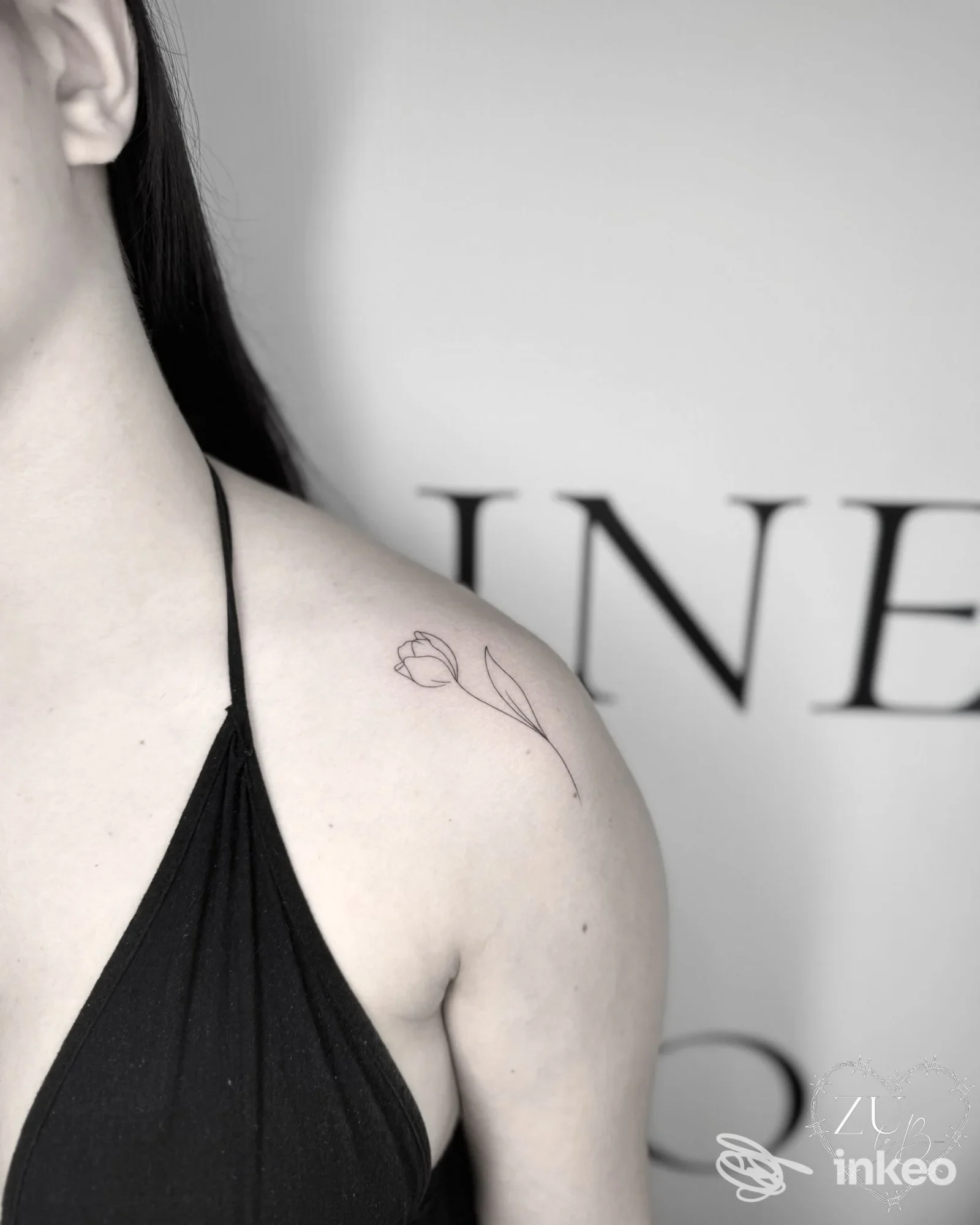 Primo piano di una spalla con piccolo tatuaggio floreale lineare, foto fornita da Ink Studio Civico 13 by Santa a Santa Margherita Ligure.