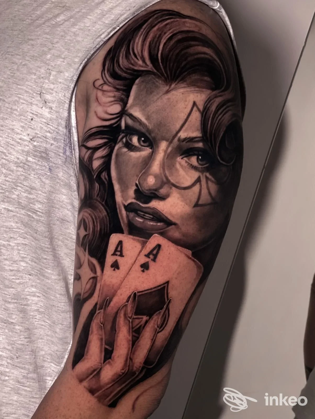 Tatuaggio ritratto realistico di donna con carte sul braccio superiore, realizzato da Black Storm Tattoo Studio a Tivoli.