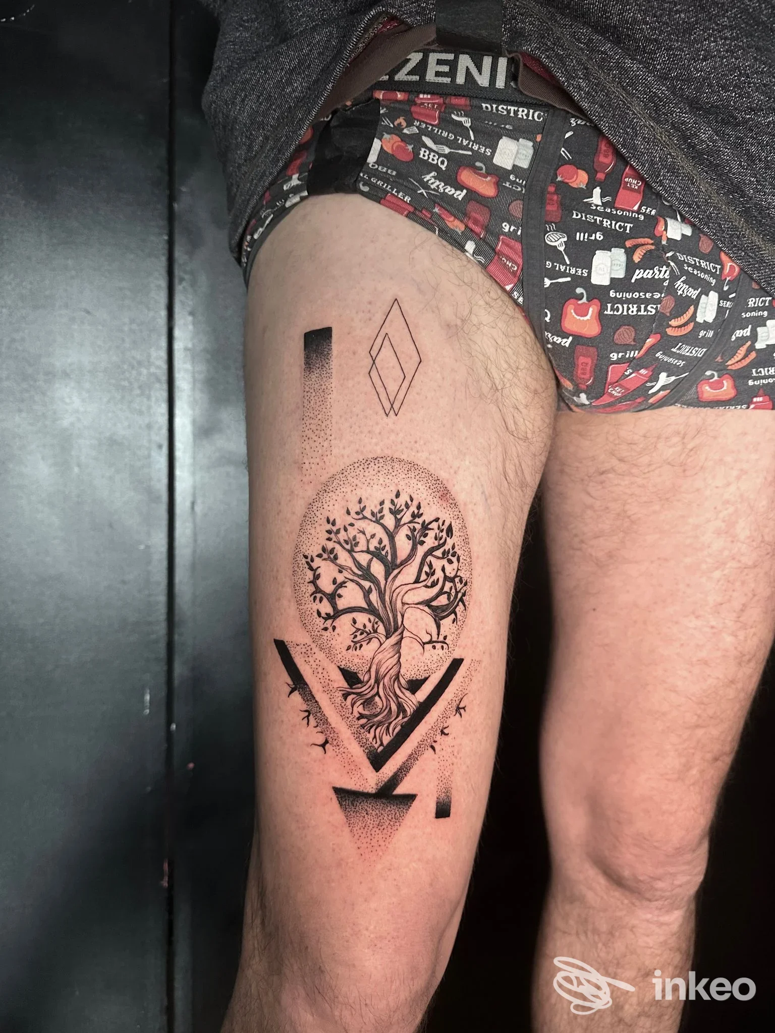 Tatuaggio albero stilizzato con elementi geometrici sulla coscia, foto fornita da BLACK VENOM TATTOO STUDIO, Roma.
