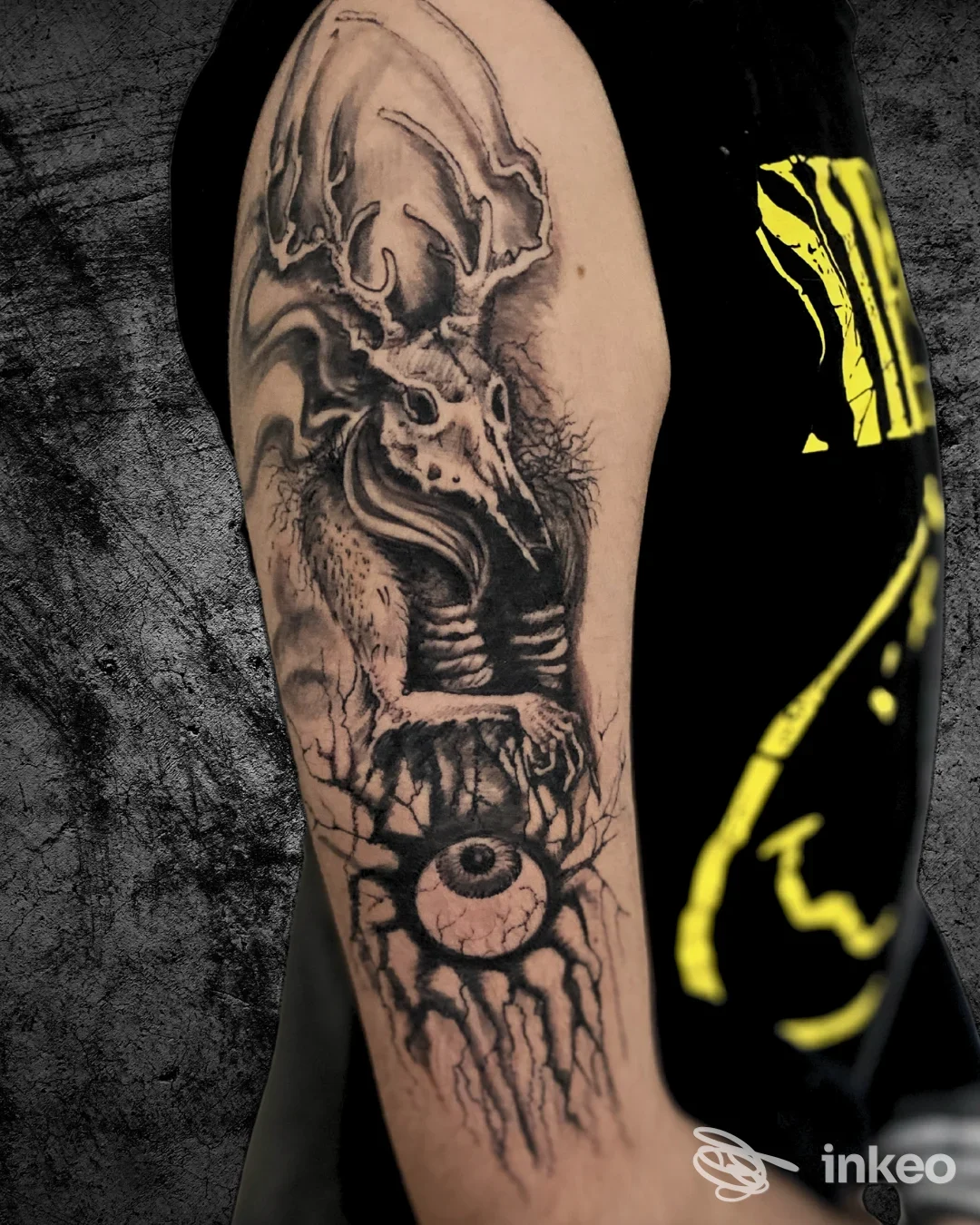 Tatuaggio in bianco e nero sul braccio superiore con cranio stilizzato e un grande occhio, foto inviata da Dany Tattoo Studio, Cerveteri.
