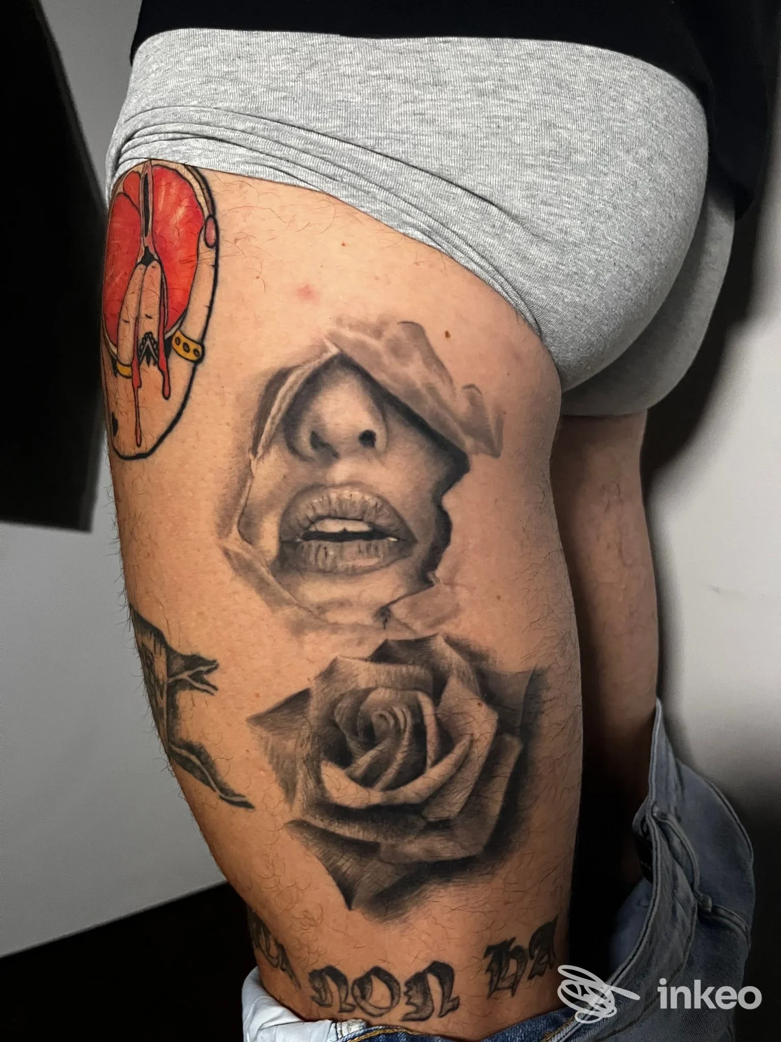 Tattoo realistico su coscia con bocca frammentata e rosa, lavoro di Valkiria Tattoo a Nettuno.