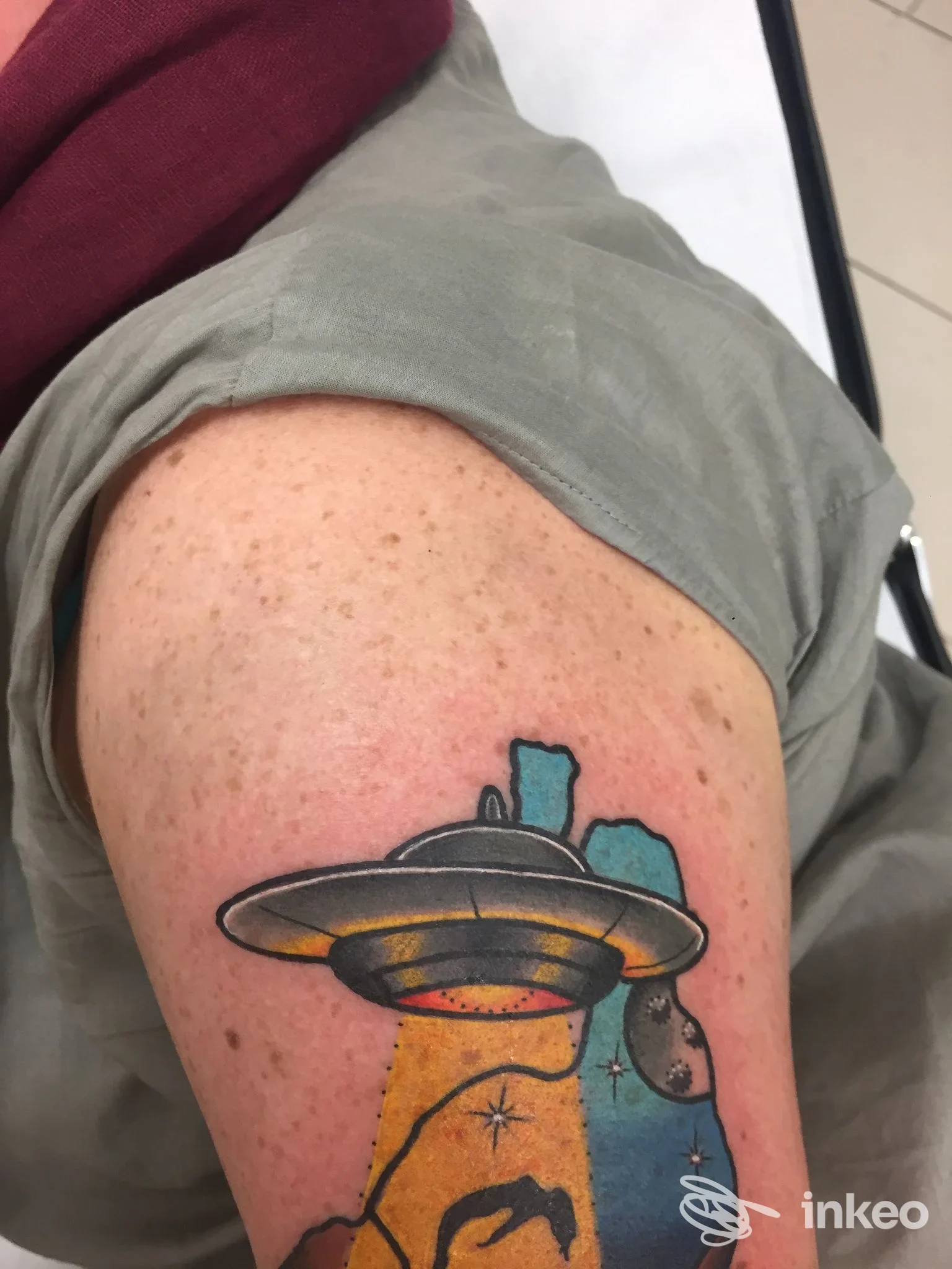 Tatuaggio colorato su braccio superiore raffigurante un disco volante con raggio, foto fornita da End8_tattoo, Novi Ligure.
