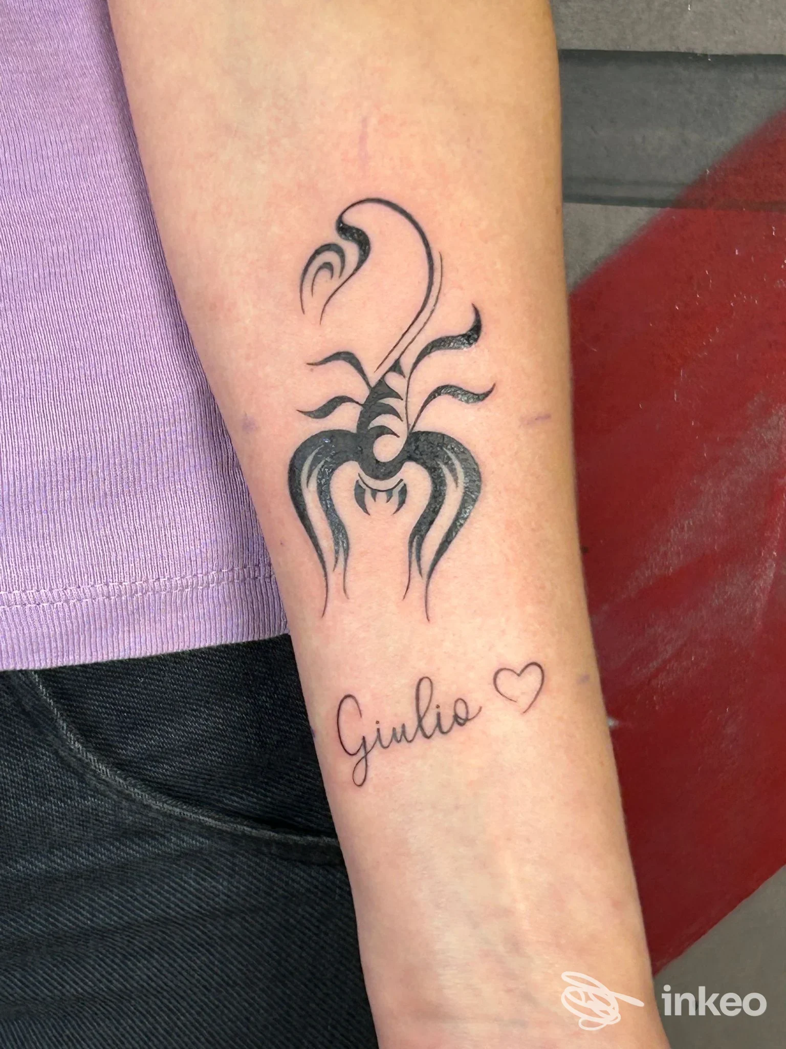 Avambraccio con tatuaggio scorpione stilizzato e scritta 'Giulio', realizzato da Officina 72 Tattoo Studio, Viterbo.