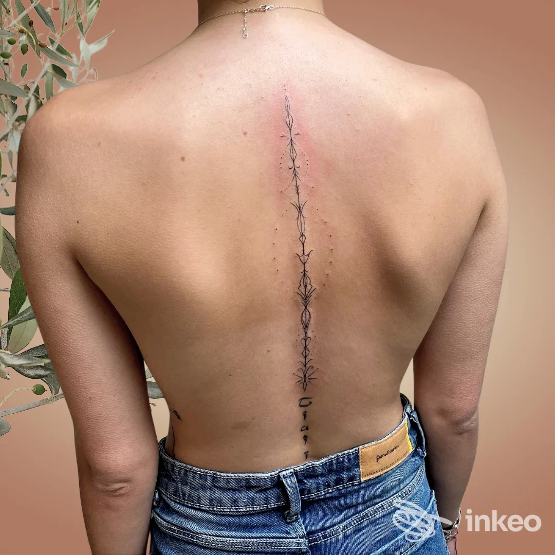 Schiena nuda con tatuaggio sottile e decorativo lungo la colonna vertebrale, realizzato da Empyreum™ Tattoo a Ladispoli.